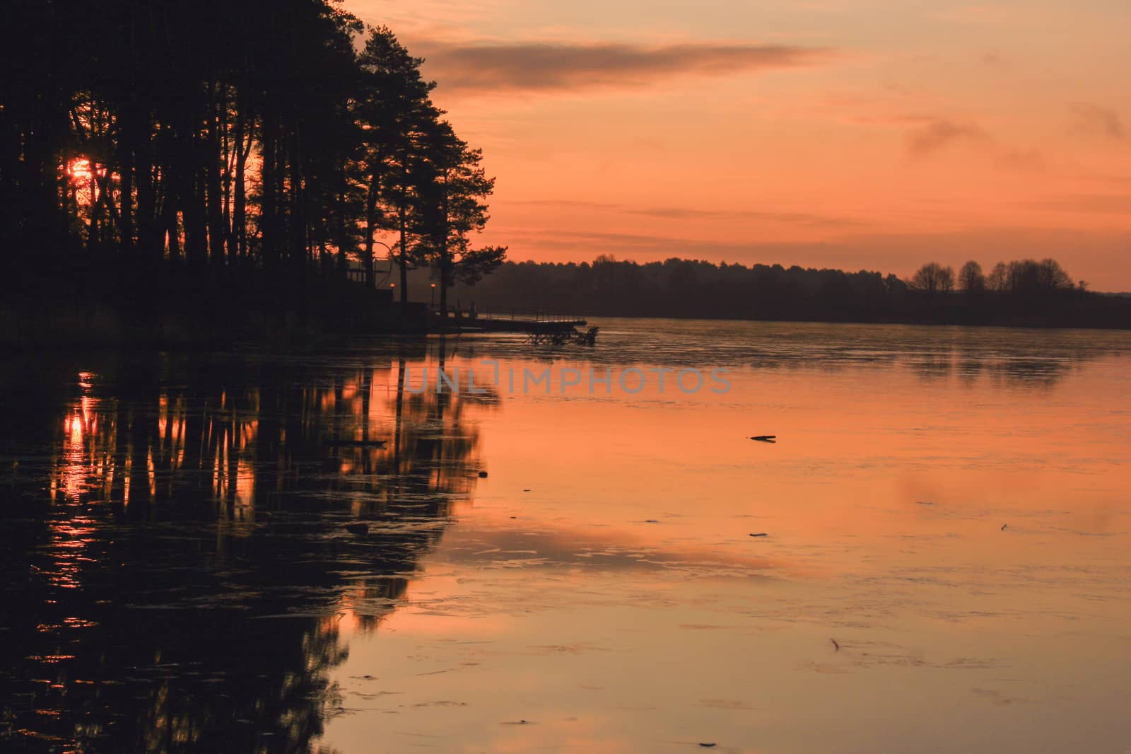 Mysterious sunset over the freezing marshy lake late autumn