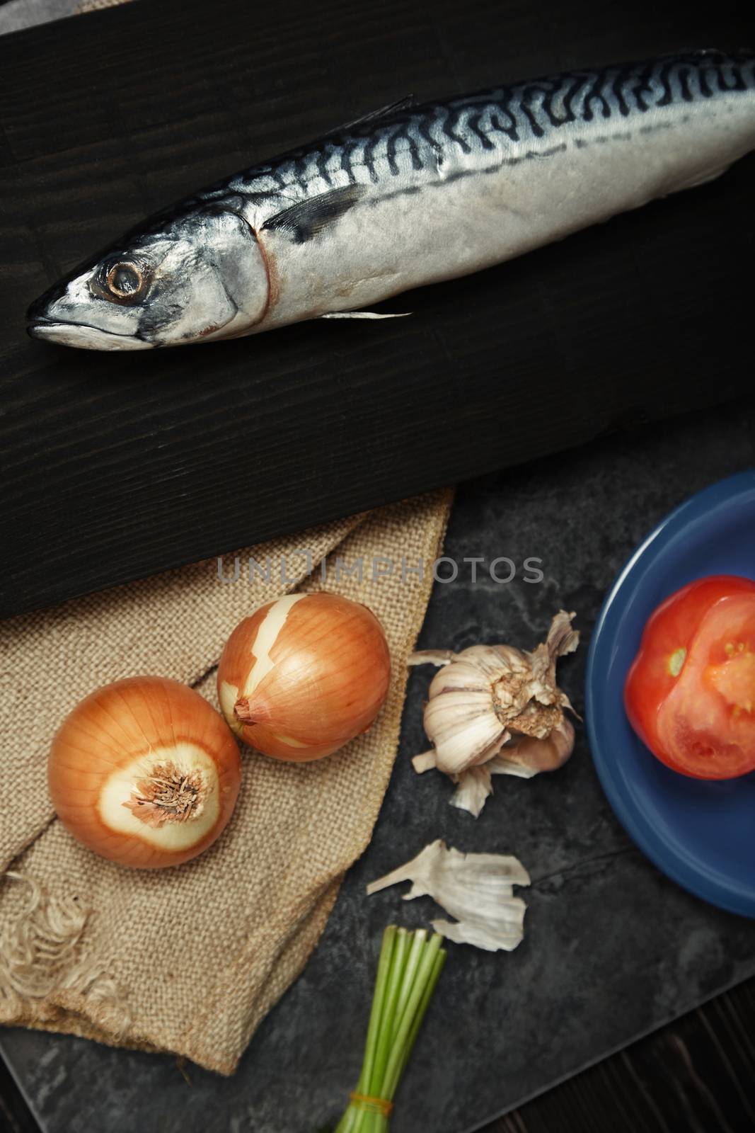 Mackerel and vegetables on a wooden table. Vertical photo