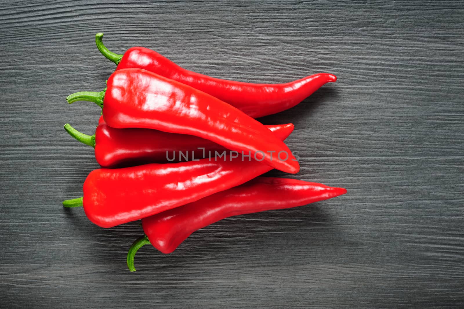 Heap of five ripe sweet red Kapia peppers on dark shale stone background, copy space