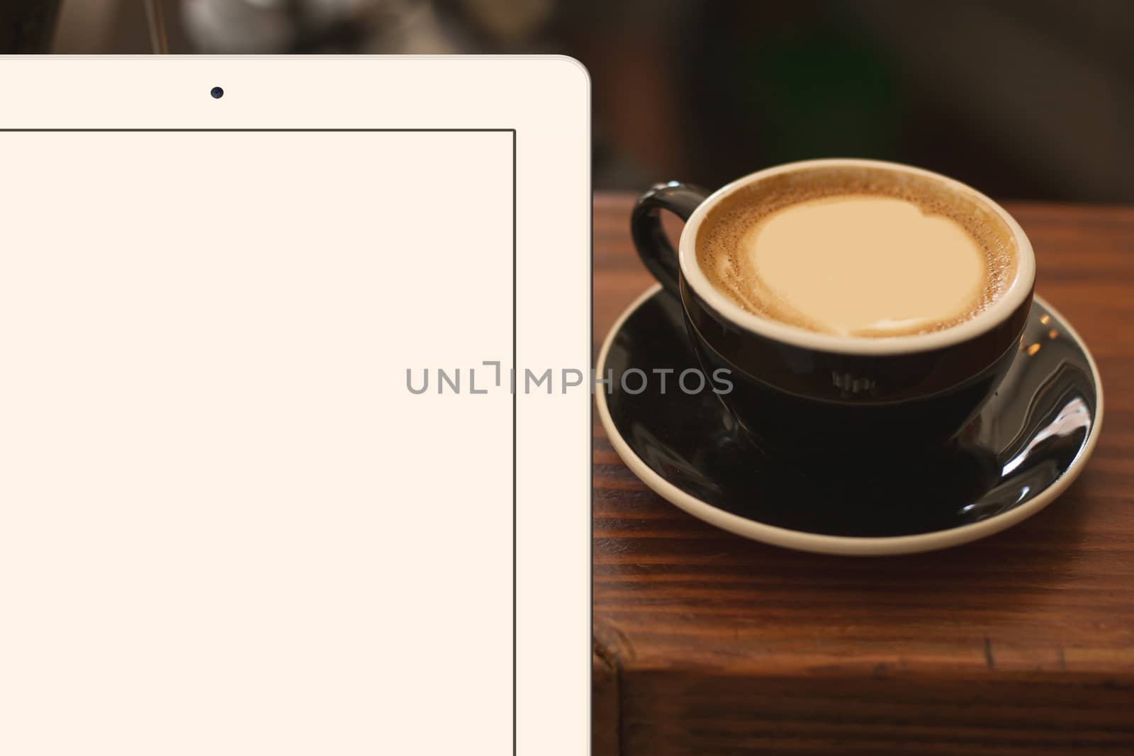 a cup of coffee and tablet in the foreground