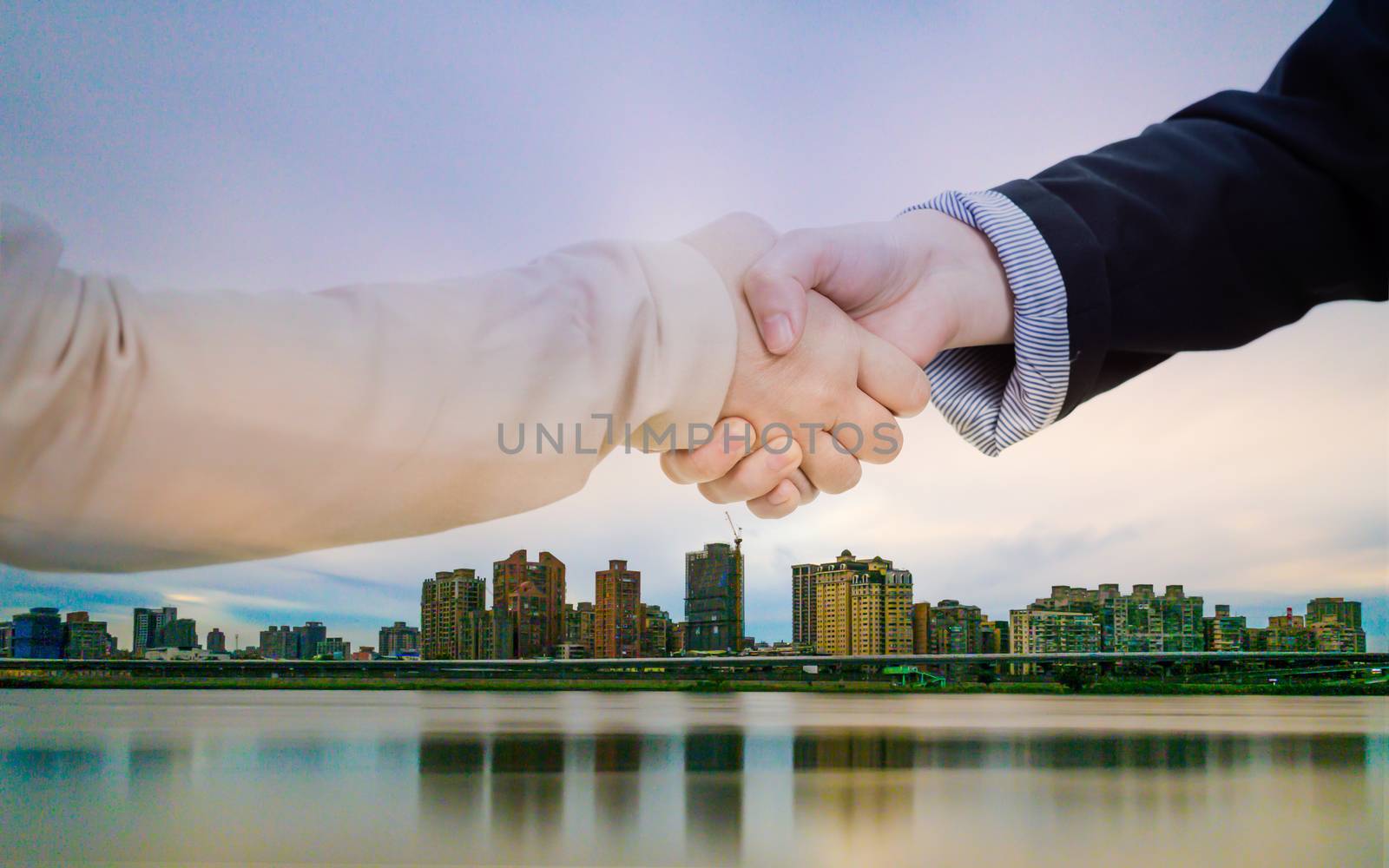 Businesswoman in casual office clothes shaking hands with cityscape double exposure