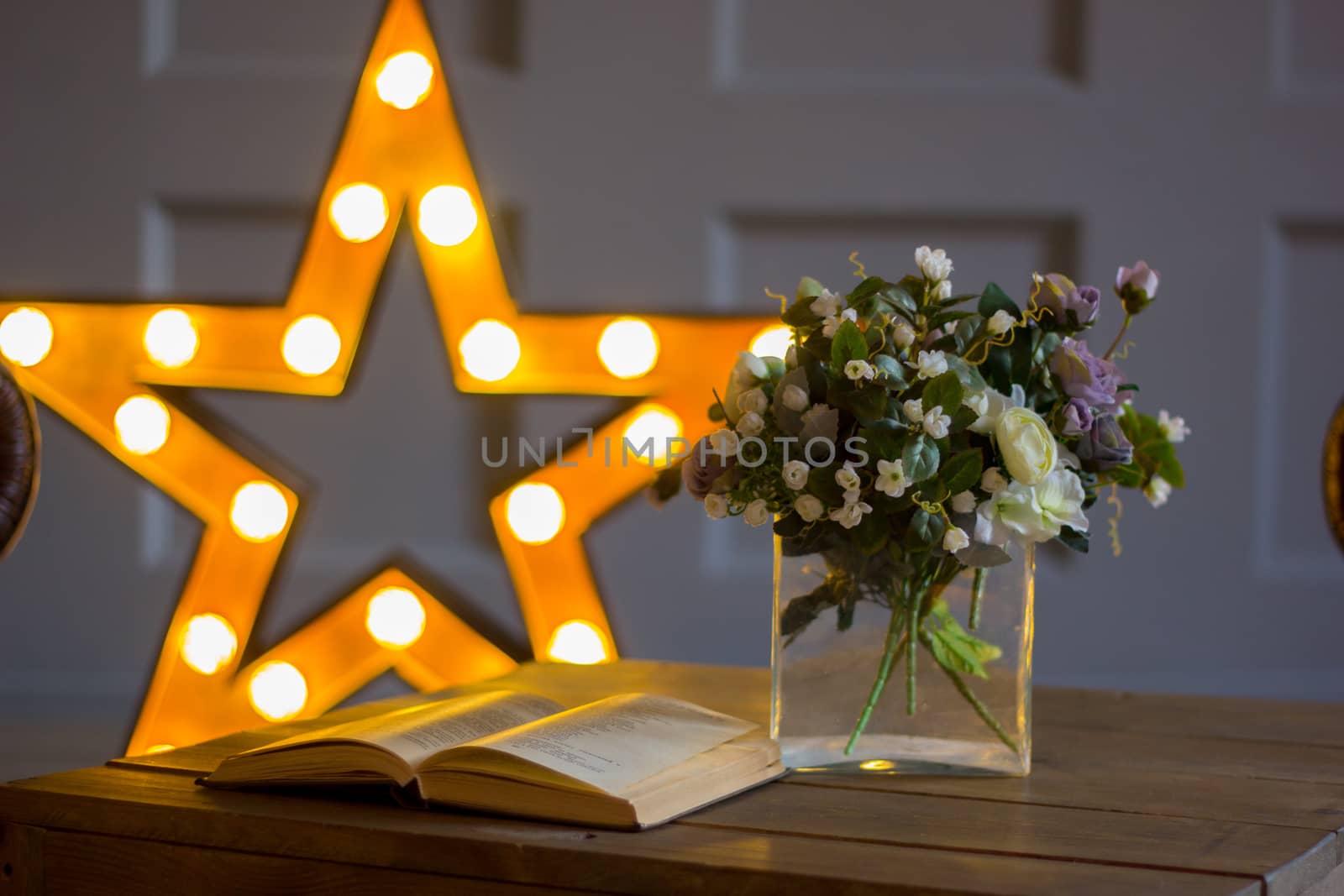 The open book on a table against the background of a star, nearby flowers