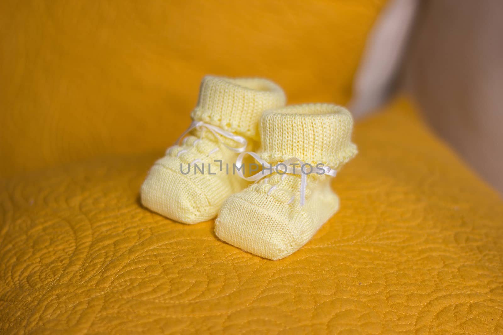 Children's yellow bootees on a yellow pillow