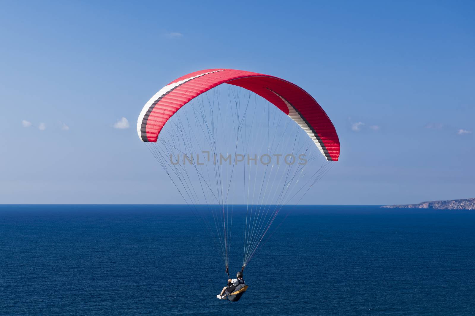 Colorful hang glider in sky over blue sea 