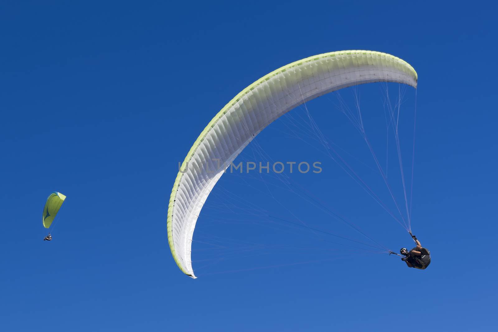 Couple of two paragliding athletes in the blue sky.