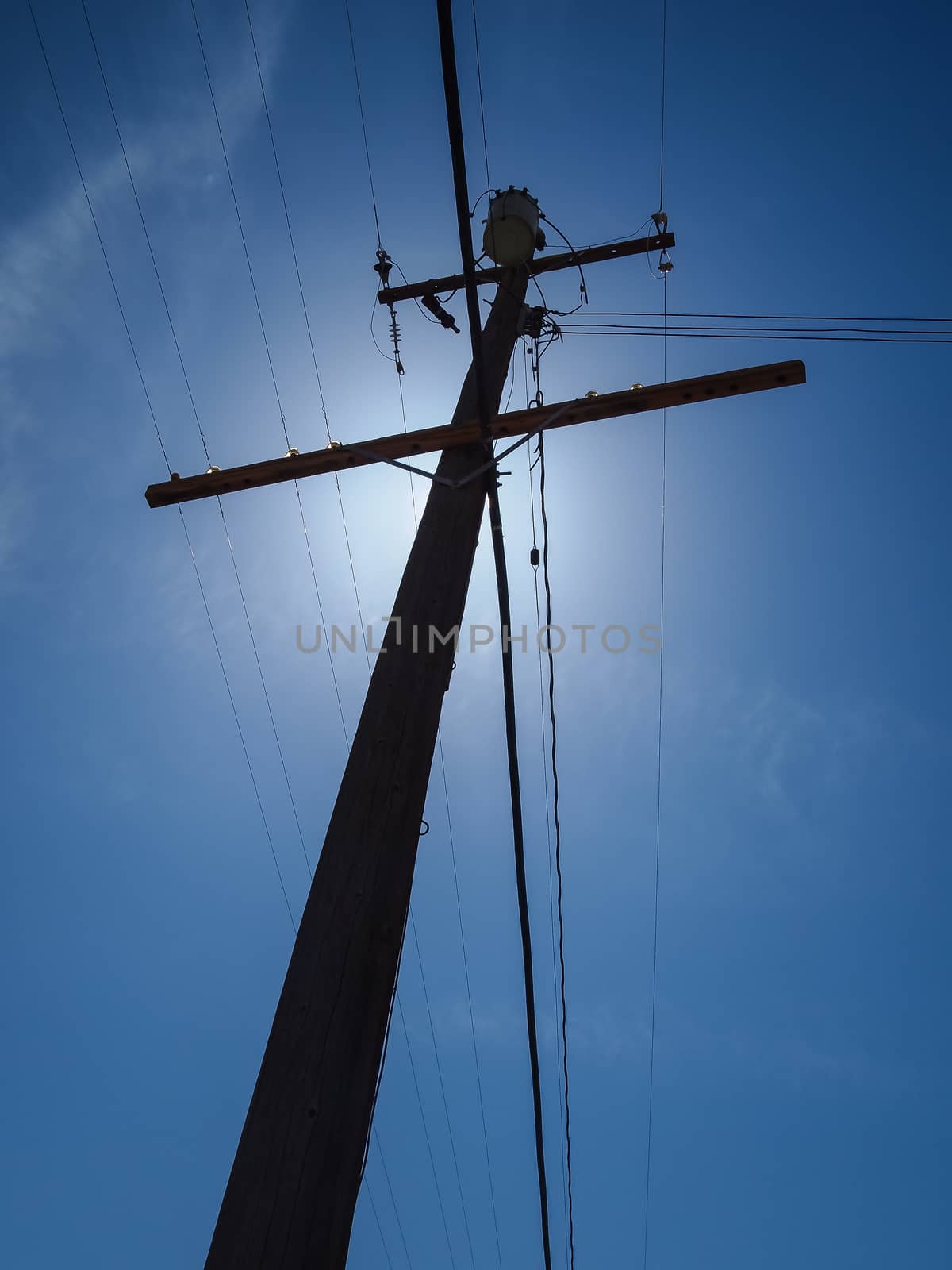 Silhouetted  electric post in blue sky background