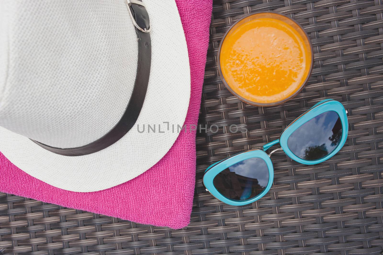 Summertime orange juice hat and sunglasses relax near swimming p by nopparats