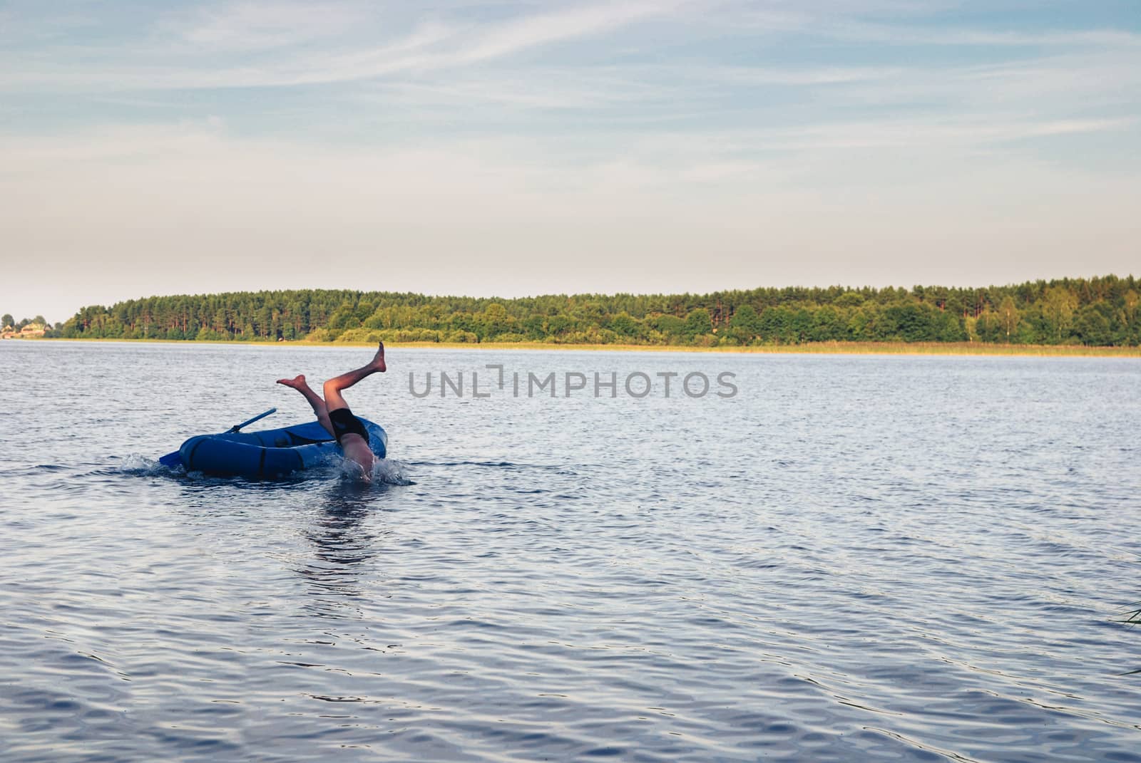 Man falling from the rubber boat to water of lake. Nature landscape by skrotov