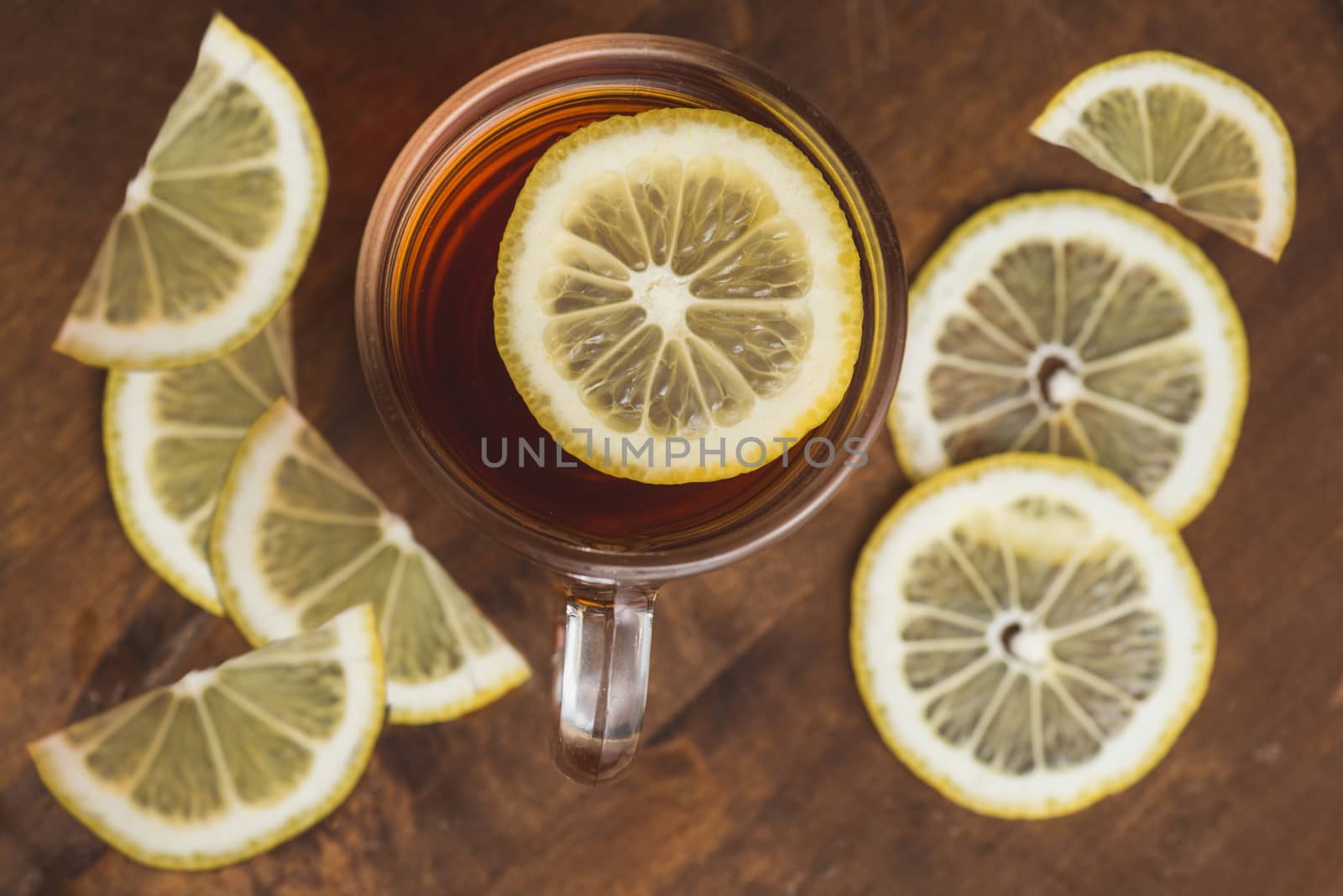 Top view of black tea with lemon in cup on wooden plank table by skrotov