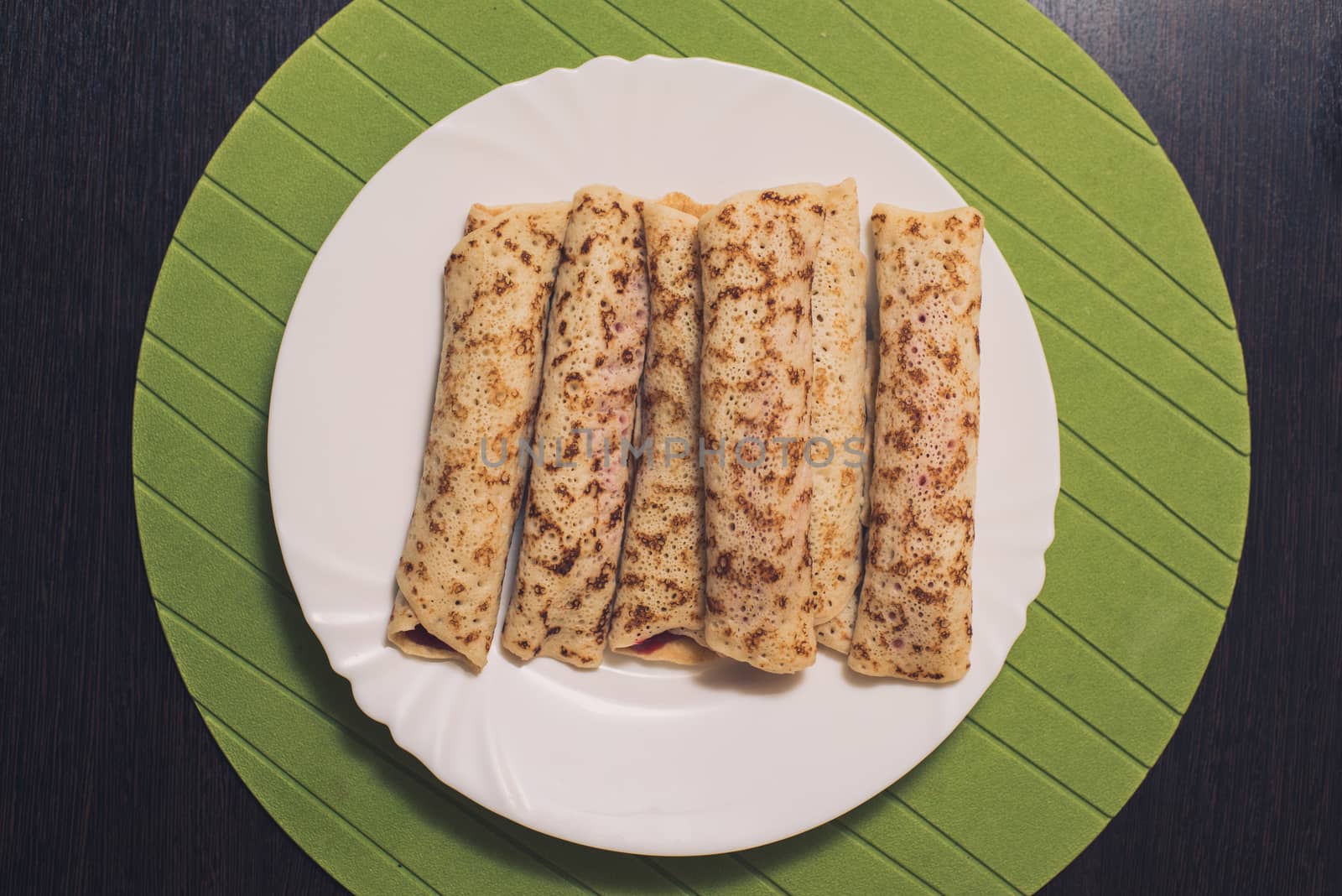 Roasted rolled pancakes on a white round plate. Top view . Flat lay.