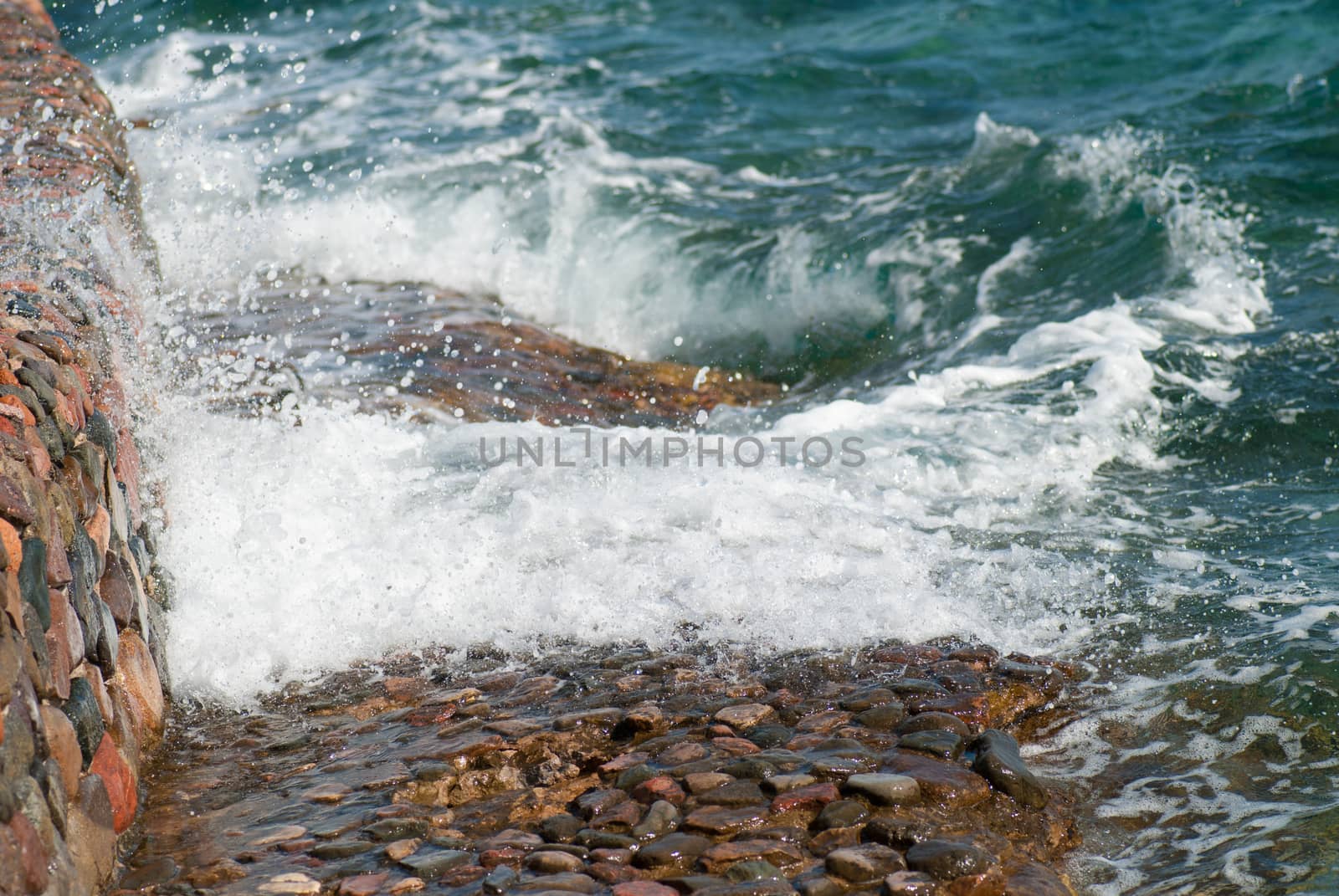 Photo of beautiful clear turquoise sea ocean water surface with ripples and bright splash on stone seascape background, horizontal picture.