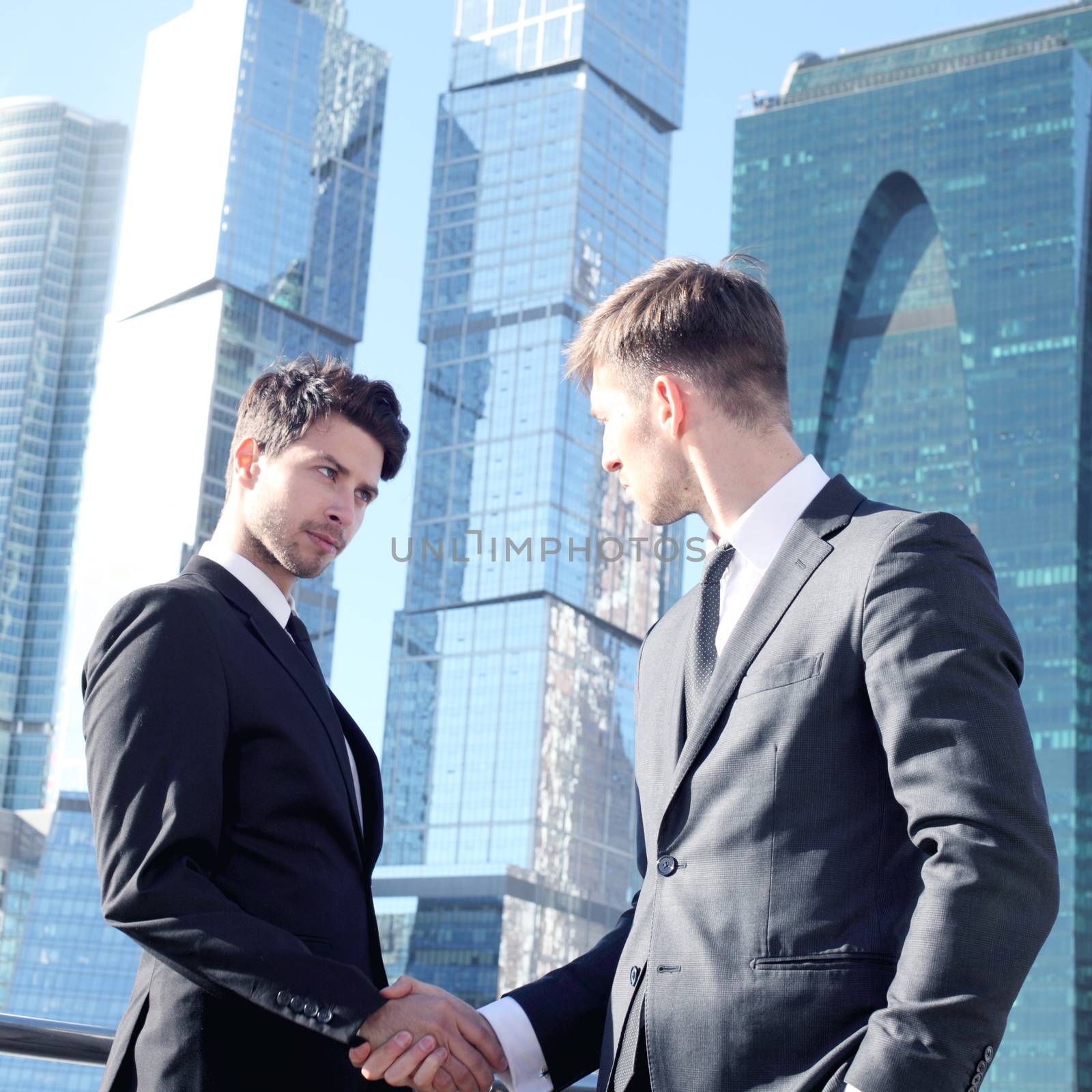 Business people shaking hands on skyscraper background