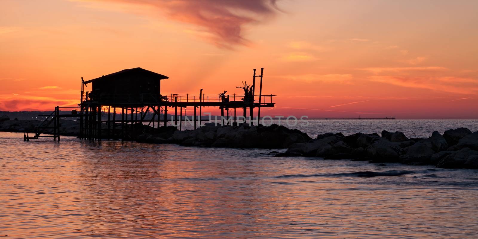 Stilt house over the sea in a beautiful red sunset