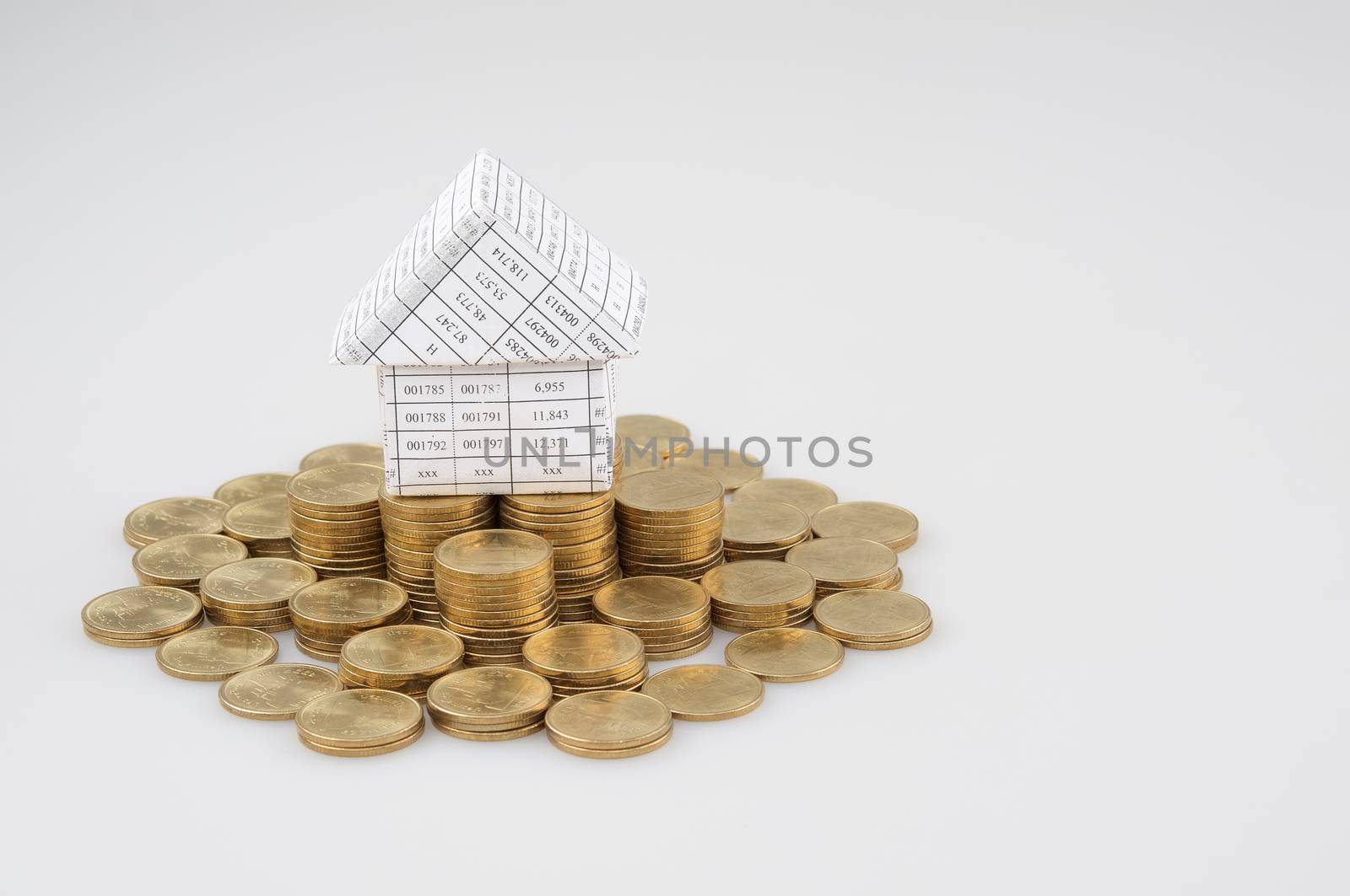 Paperwork as house place on pile of gold coins by eaglesky