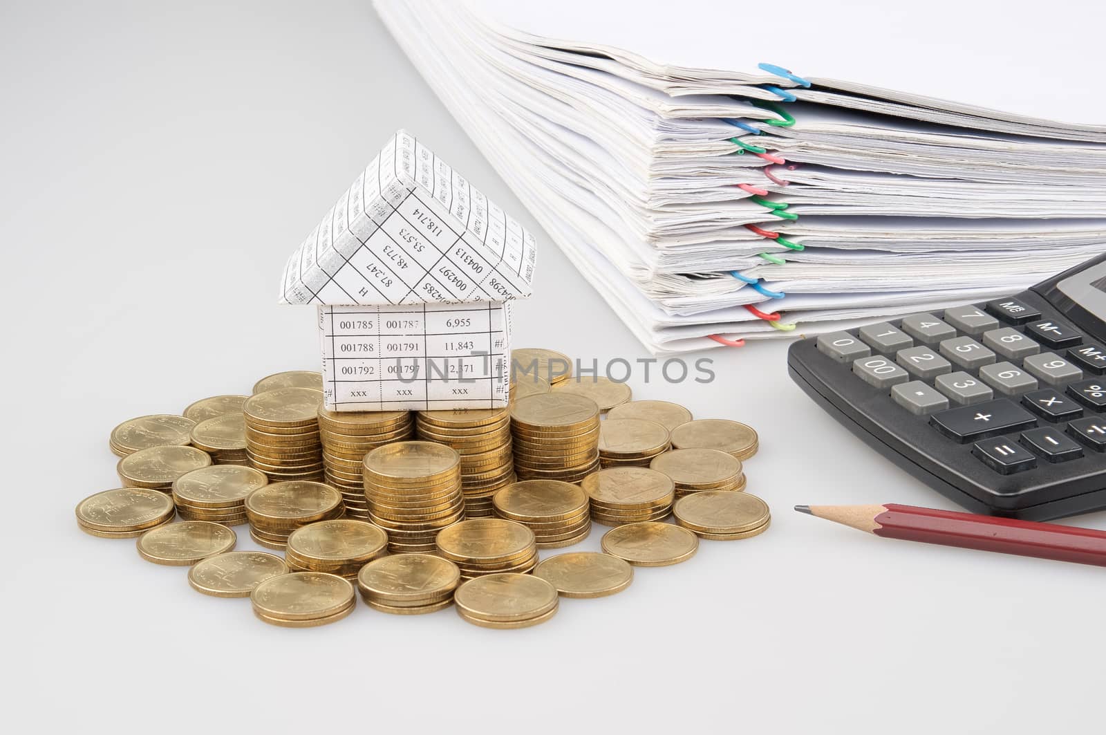 House on pile of gold coins with pencil and calculator with pile of report with colorful of paperclip place on white background. 