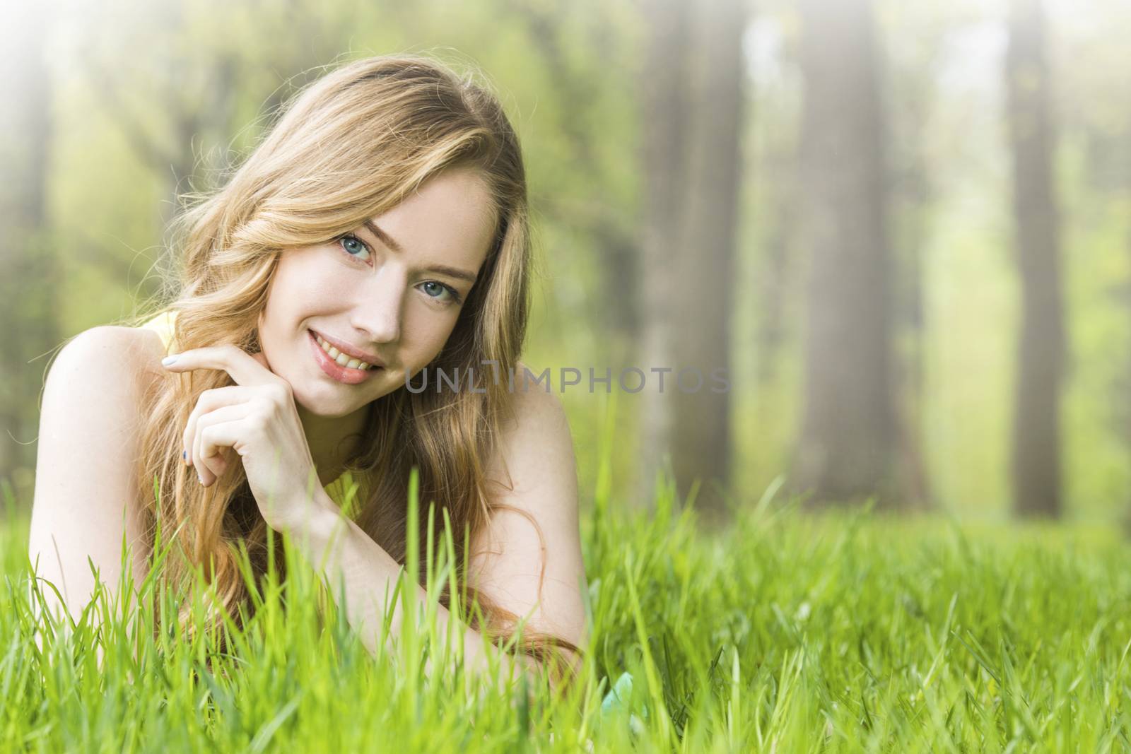 Redhead or blonde romantic beautiful young woman laying on grass in park