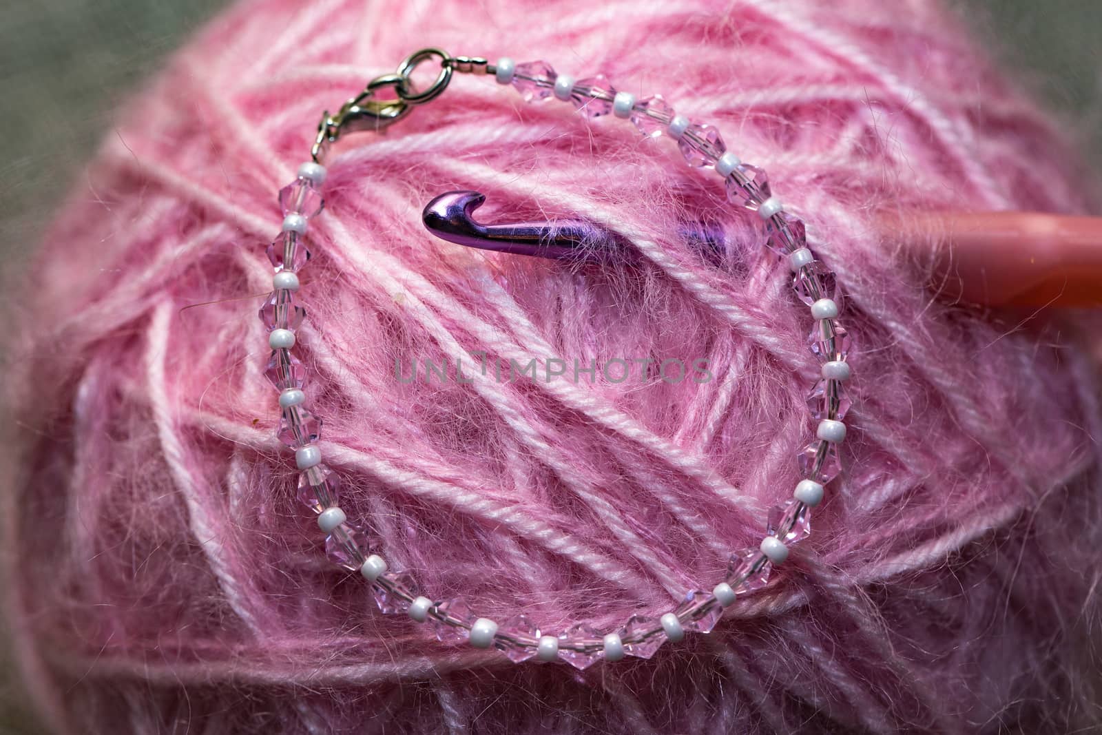 pink ball of yarn with the hook closeup
