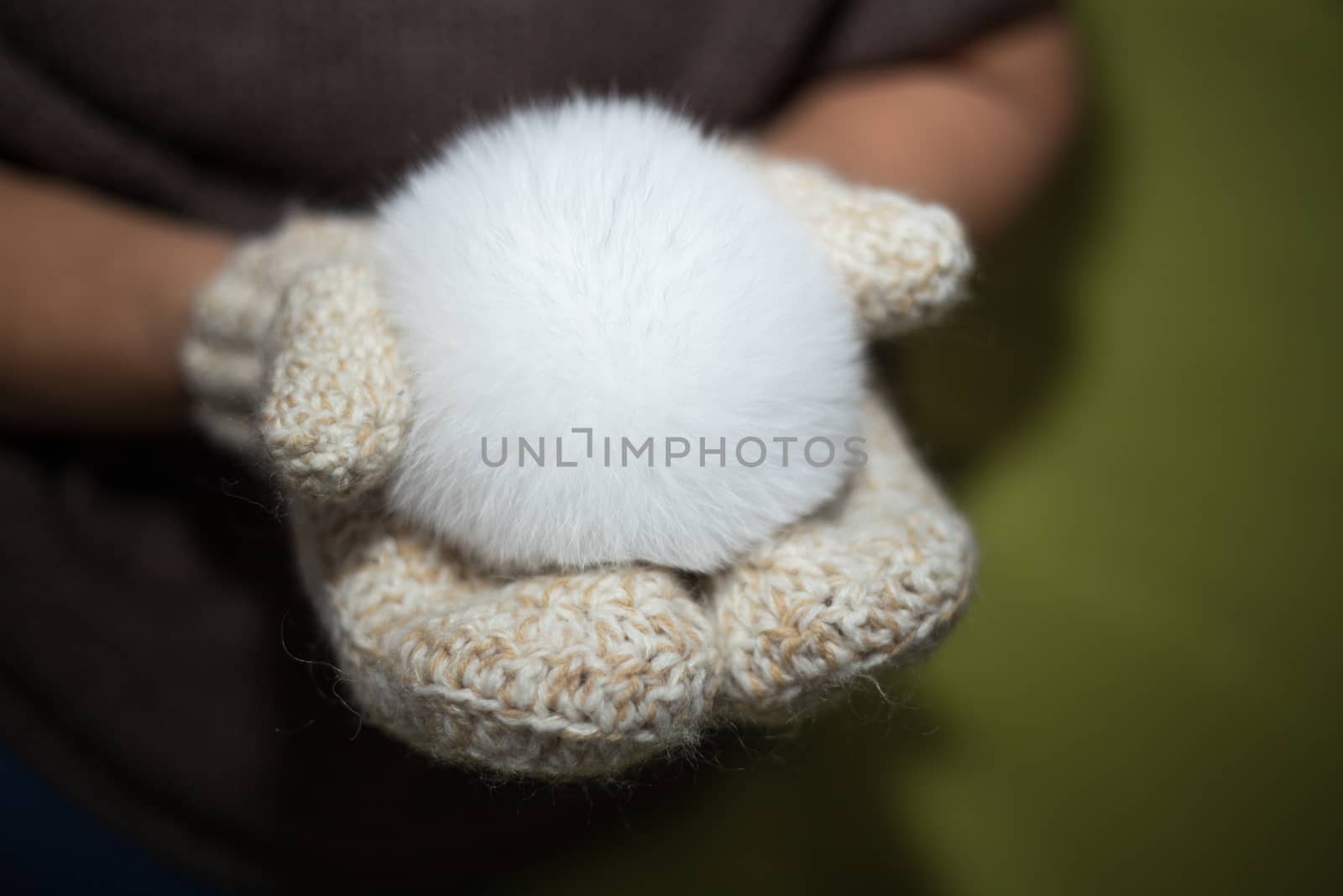 Woman wearing a knitted gloves holding a pompom. by boys1983@mail.ru