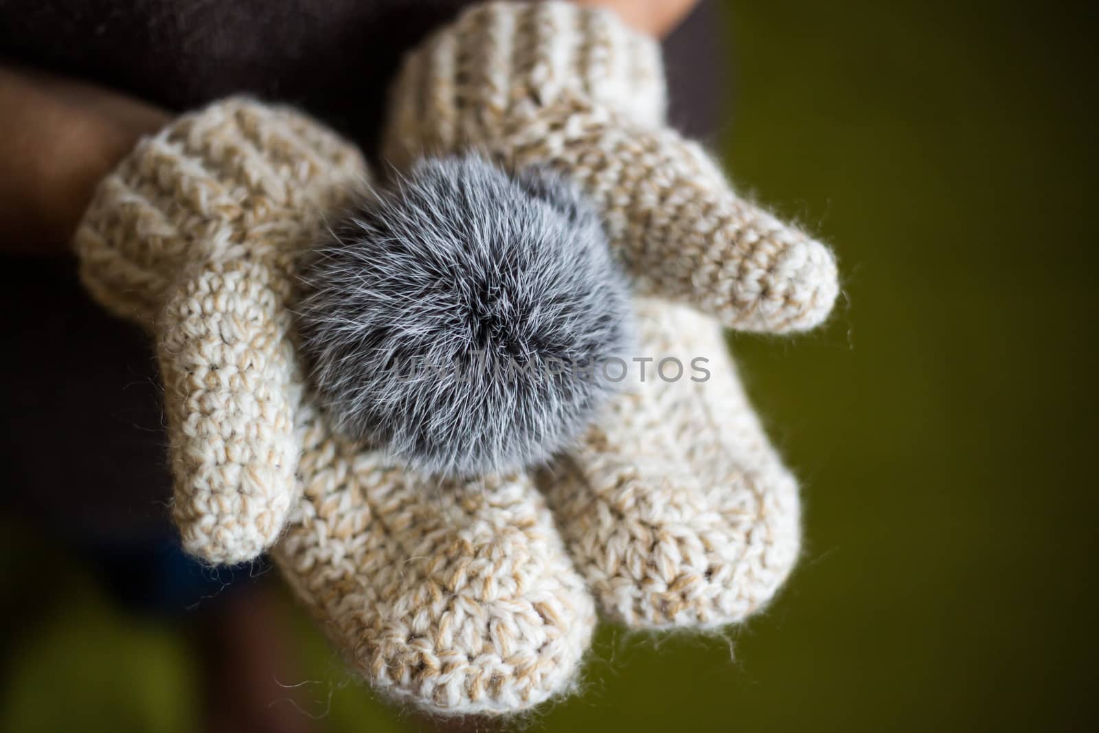 Woman wearing a knitted gloves holding a pompom. by boys1983@mail.ru