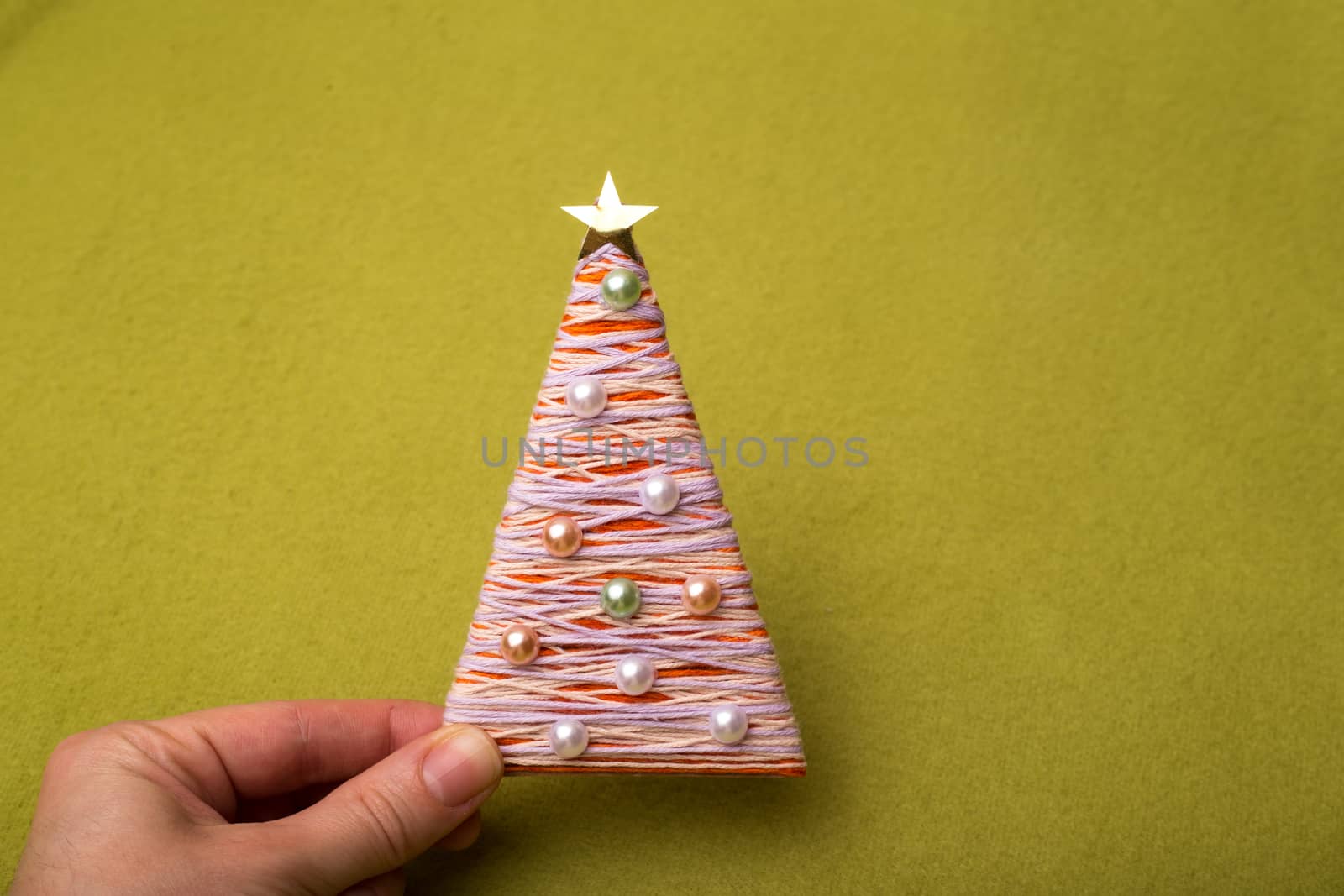 Christmas tree made of threads and beads.in the hands holding the girl