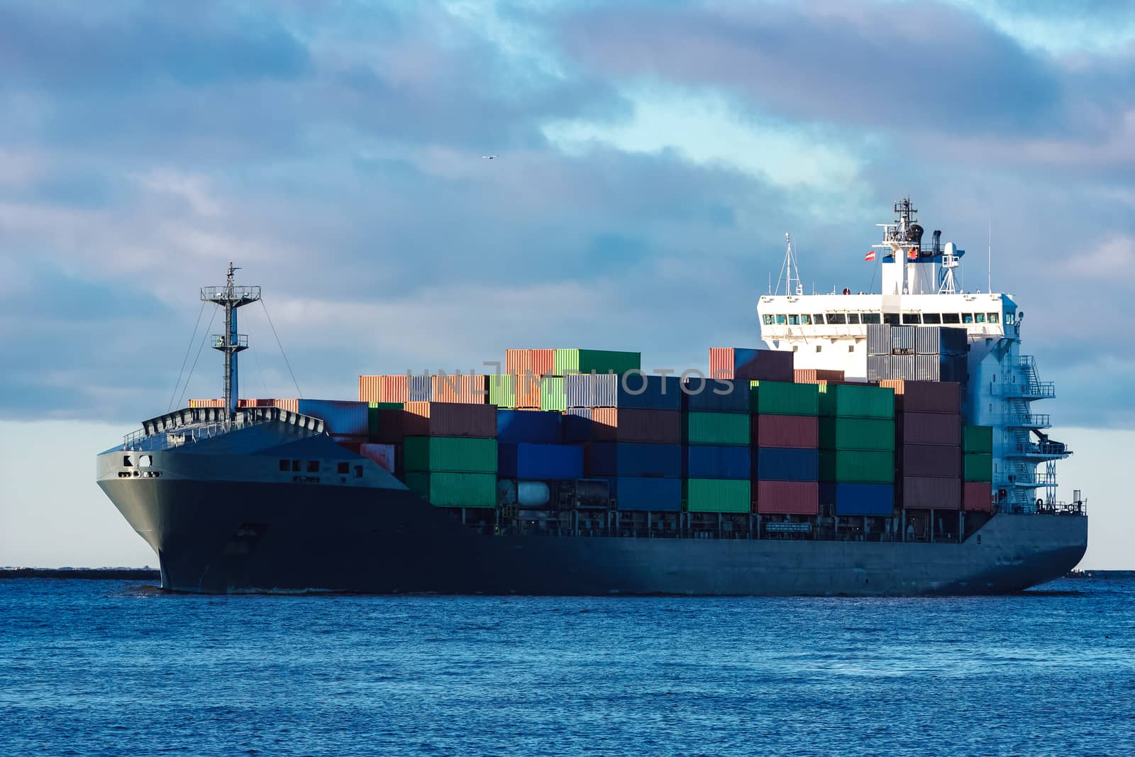 Modern grey container ship moving in still water