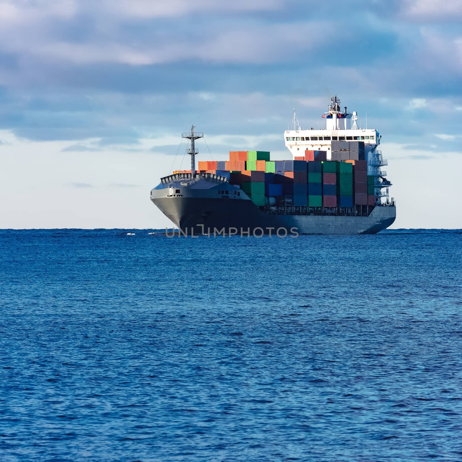 Modern grey container ship moving in still water