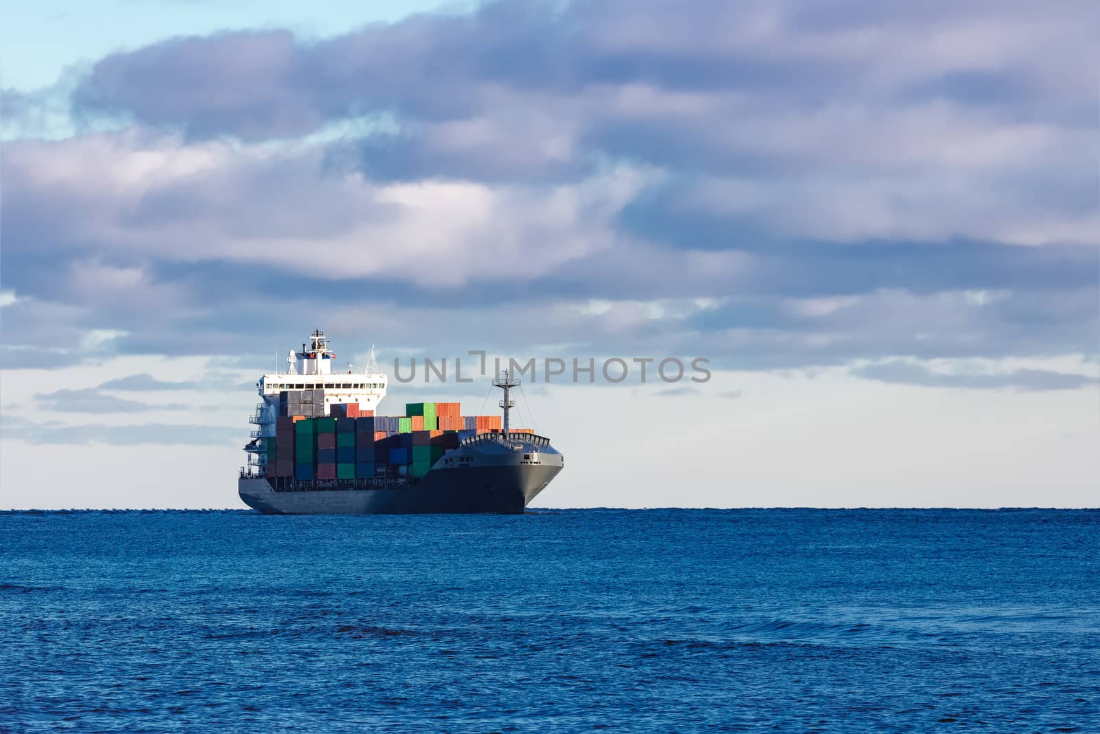 Modern grey container ship moving in still water