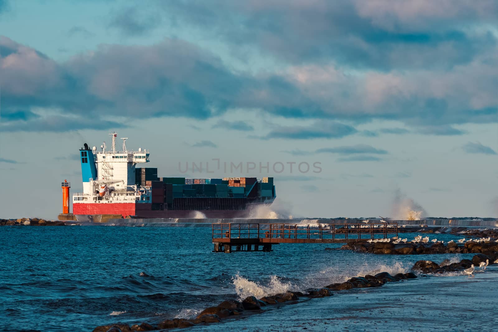 Full red container ship moving in stormy weather