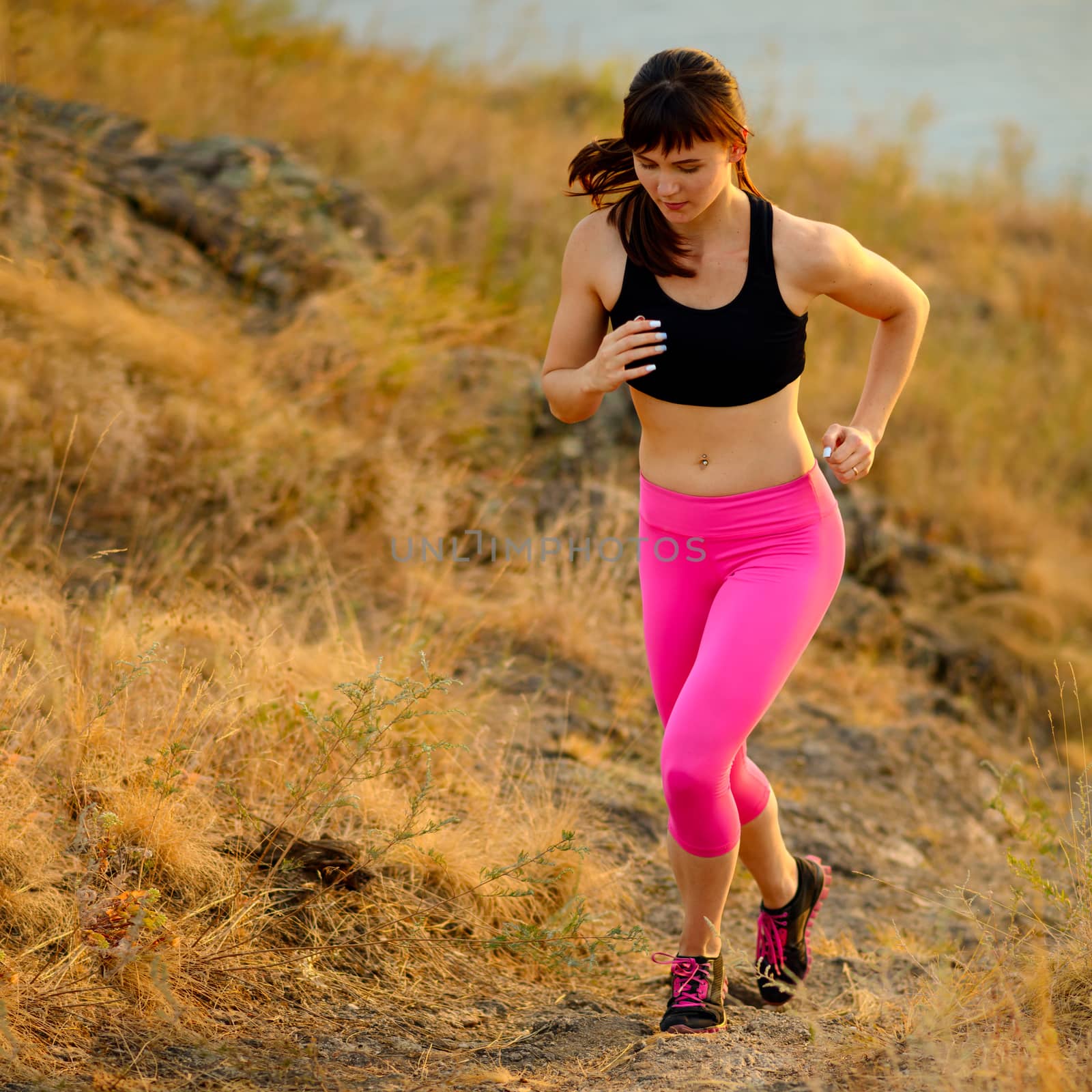 Young Woman Running on the Morning Mountain Trail. Active Lifestyle Concept. by maxpro