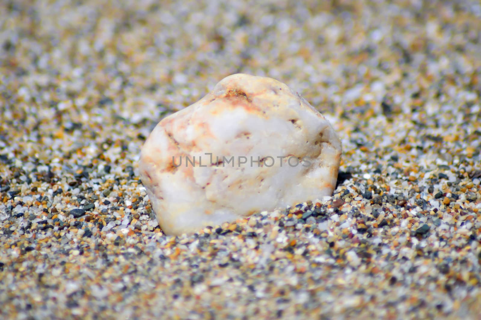 One pebbles on a background of grains of sand on the beach of Amoudara