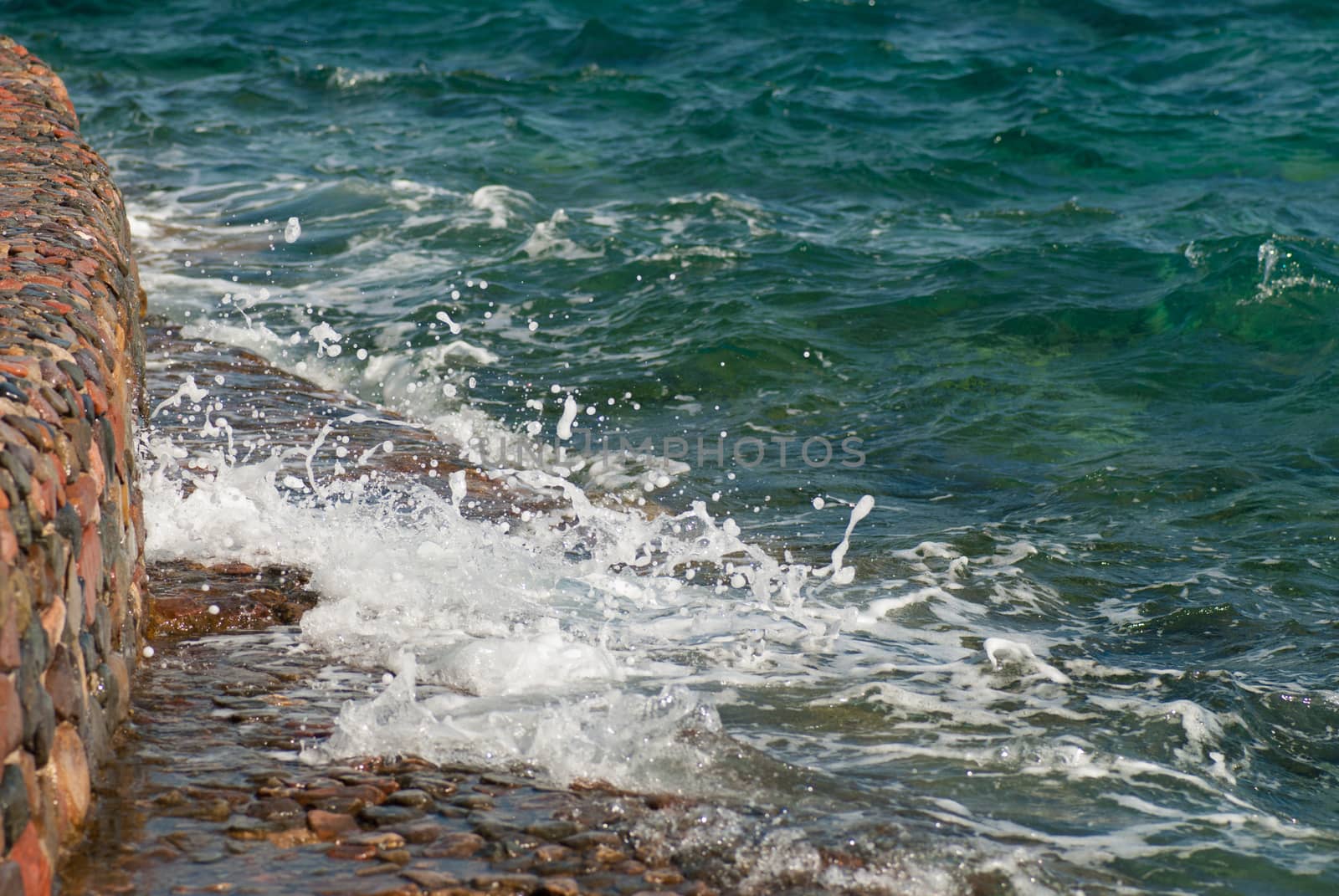 Photo of beautiful clear turquoise sea ocean water surface with ripples and bright splash on stone seascape background, horizontal picture by skrotov