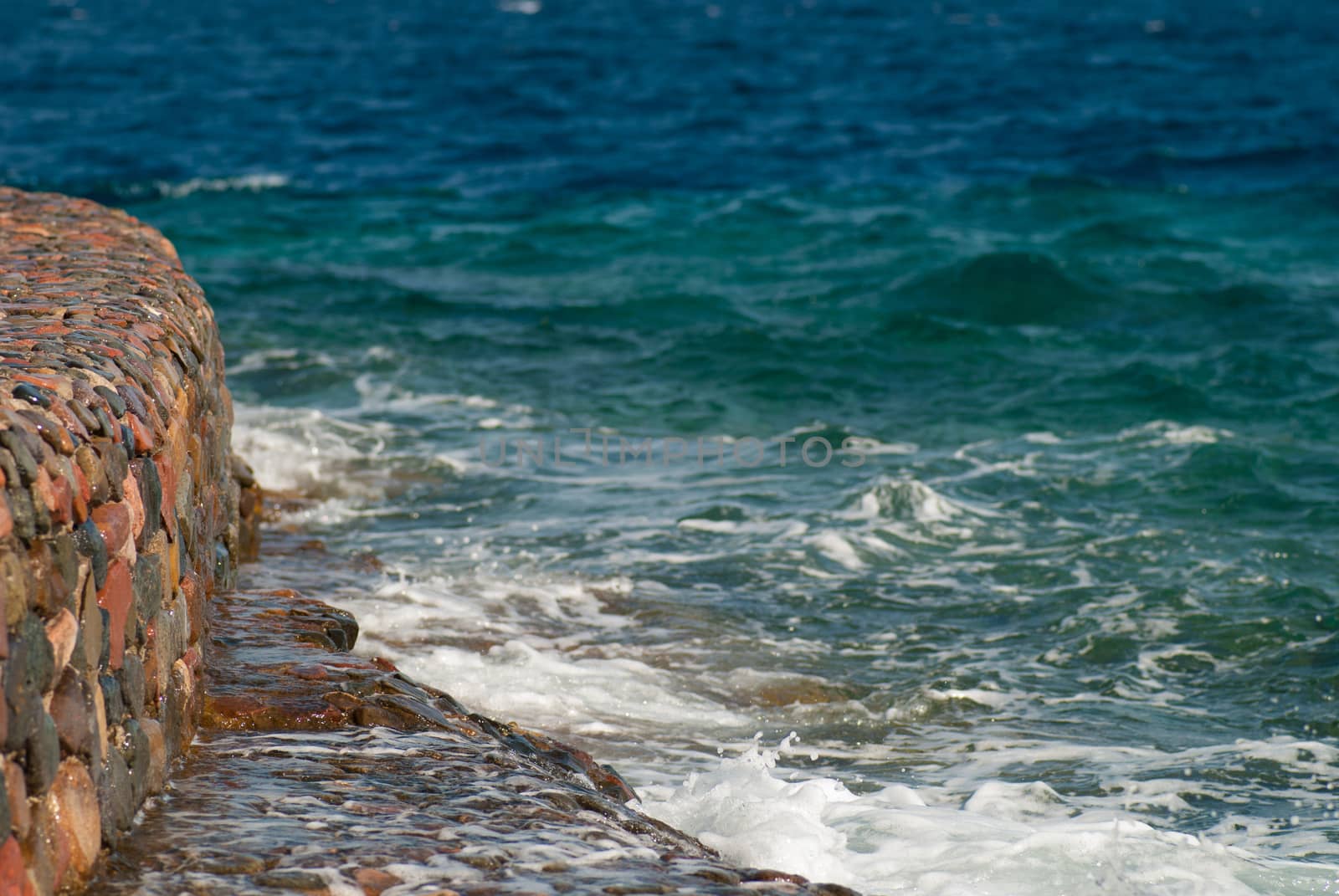 Photo of beautiful clear turquoise sea ocean water surface with ripples and bright splash on stone seascape background, horizontal picture by skrotov