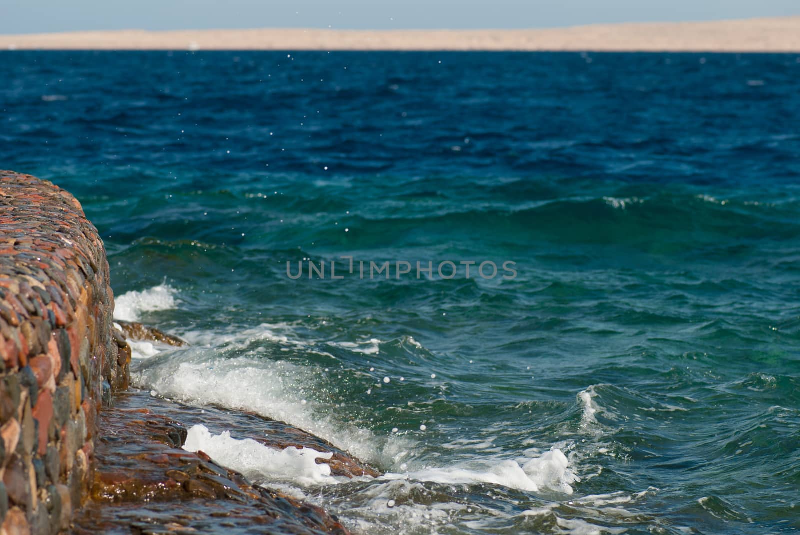 Photo of beautiful clear turquoise sea ocean water surface with ripples and bright splash on stone seascape background, horizontal picture by skrotov