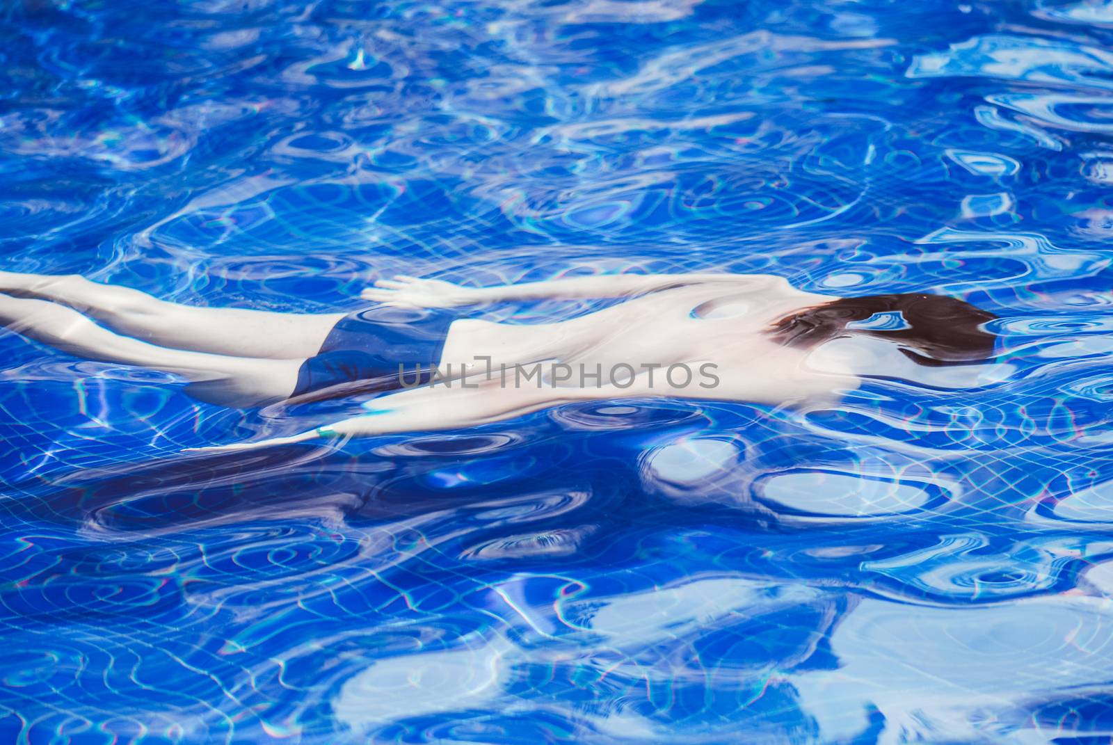 Young man swimming in the pool underwater.