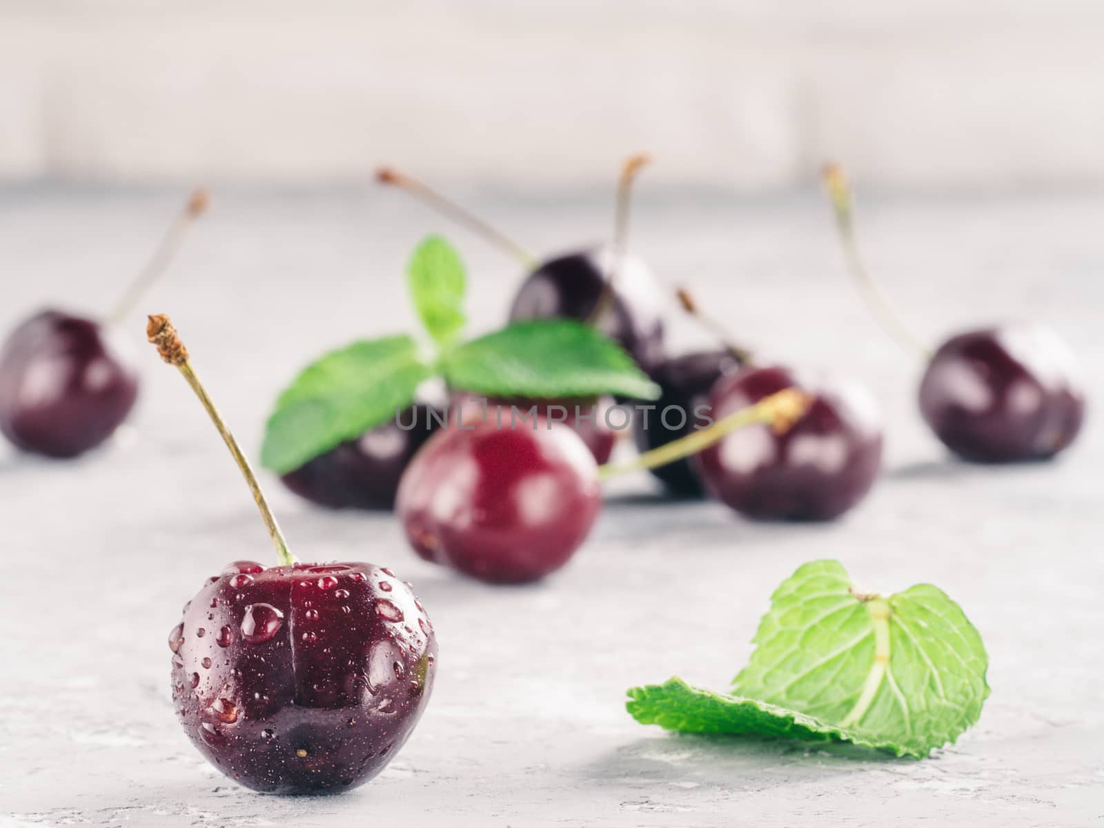 Close up view of fresh ripe cherry. Cherry and mint leaf on gray concrete background. Copy space.