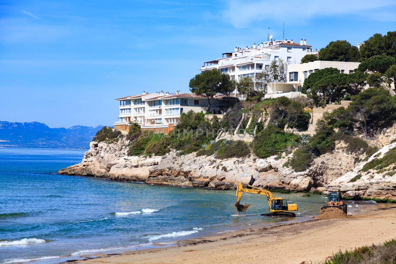 View of the empty beach with the bulldozer and the excavator. Salou, Spain