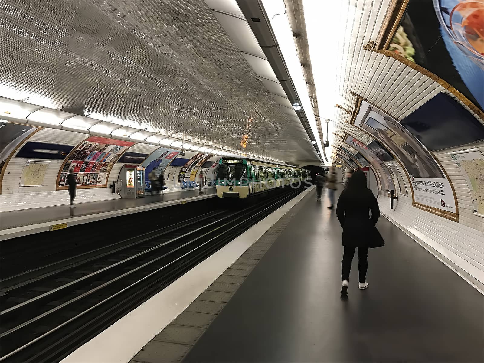 A woman walks along the platform waiting for a train ride on the metro.