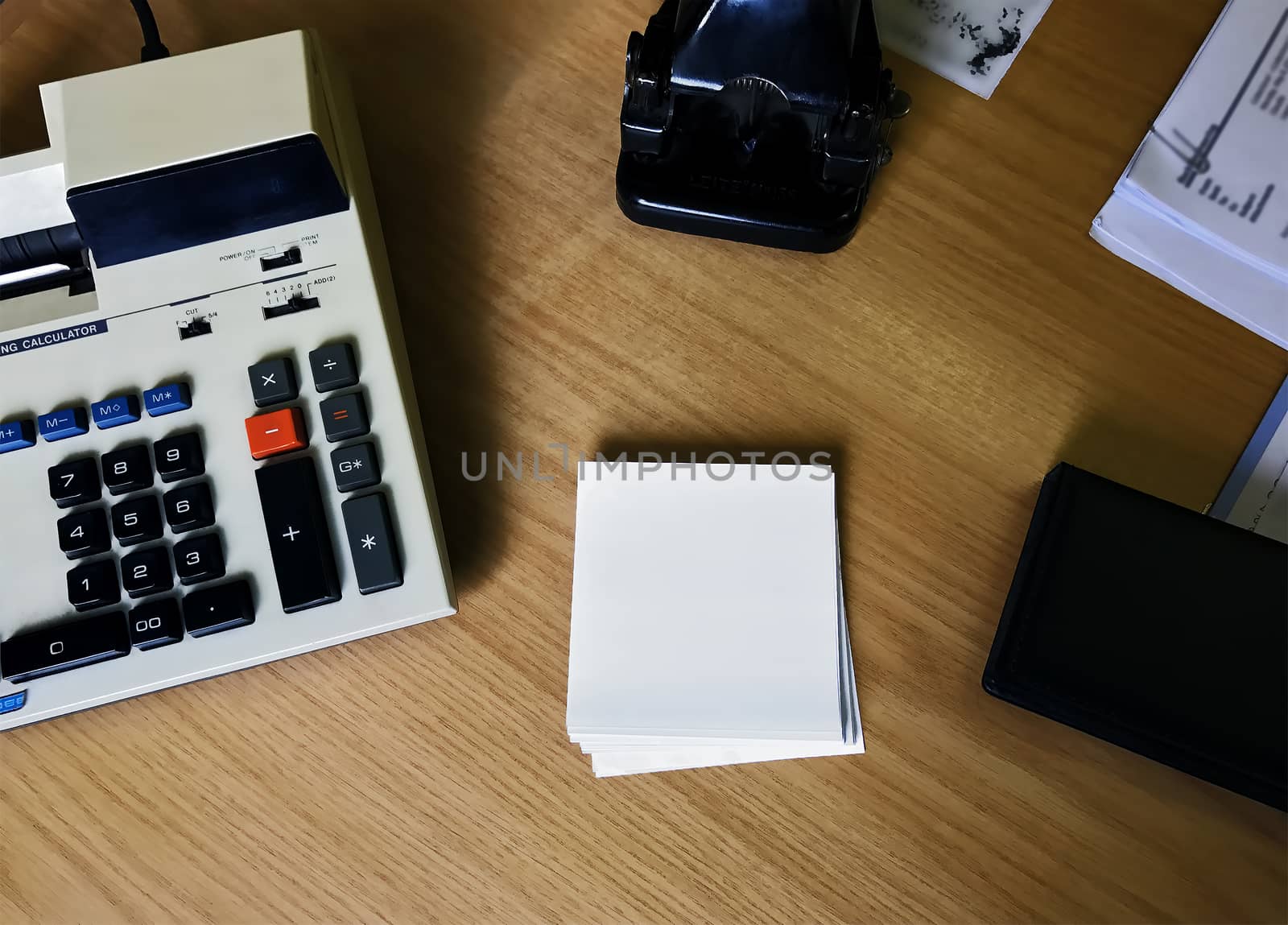 Office desk with a retro calculator and paper punch.