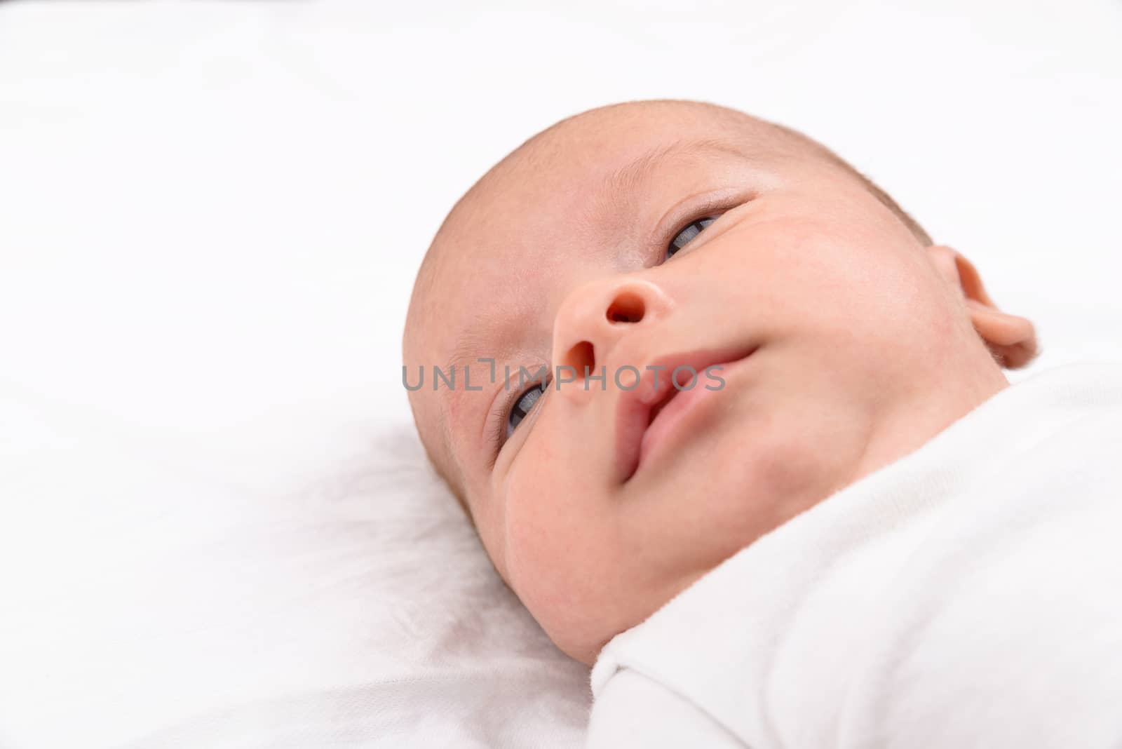 Newborn baby on white sheet by dutourdumonde