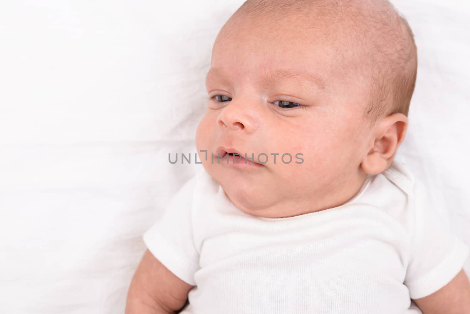 Newborn baby on white sheet by dutourdumonde