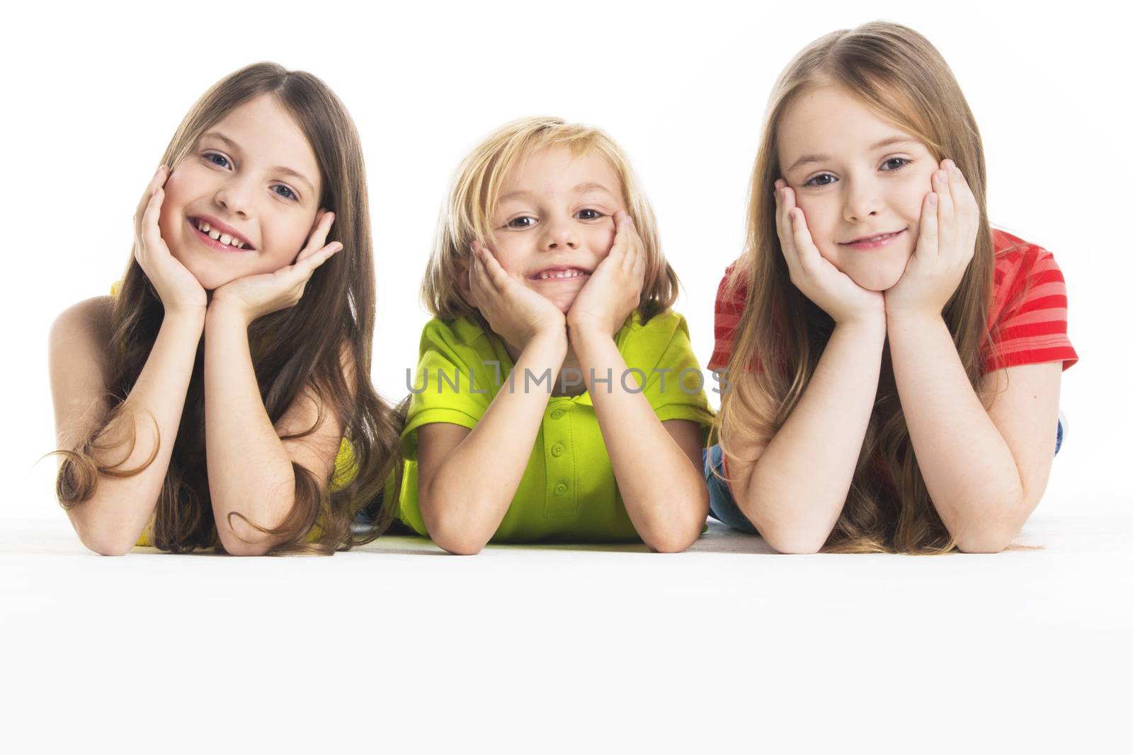 Three happy children laying down, isolated on white background