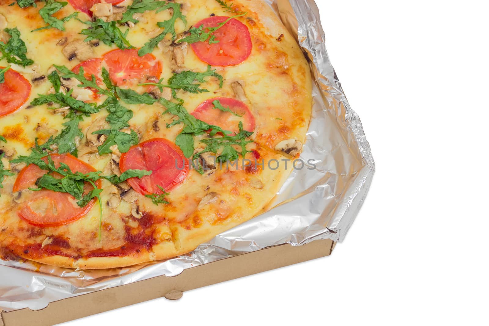 Fragment of the cooked round pizza with tomatoes, mushrooms and arugula wrapped in aluminum foil in the open cardboard box on a light background
