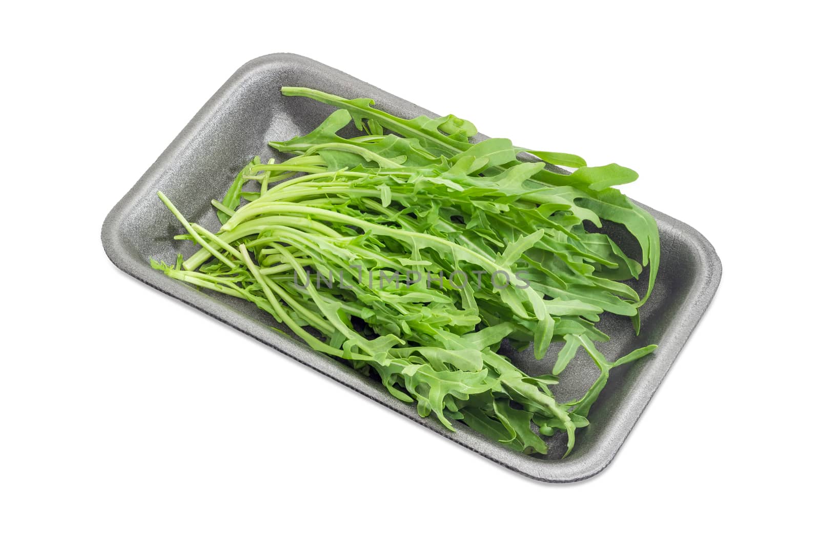 Leaves of the fresh arugula in the dark foam food container on a light background
