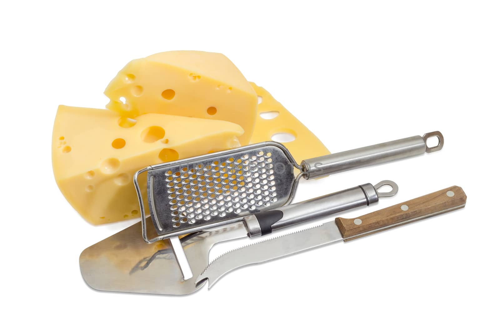 Cheese knife, cheese slicer, cheese grater against the background of the pieces semi-hard Swiss-type cheese on a light background
