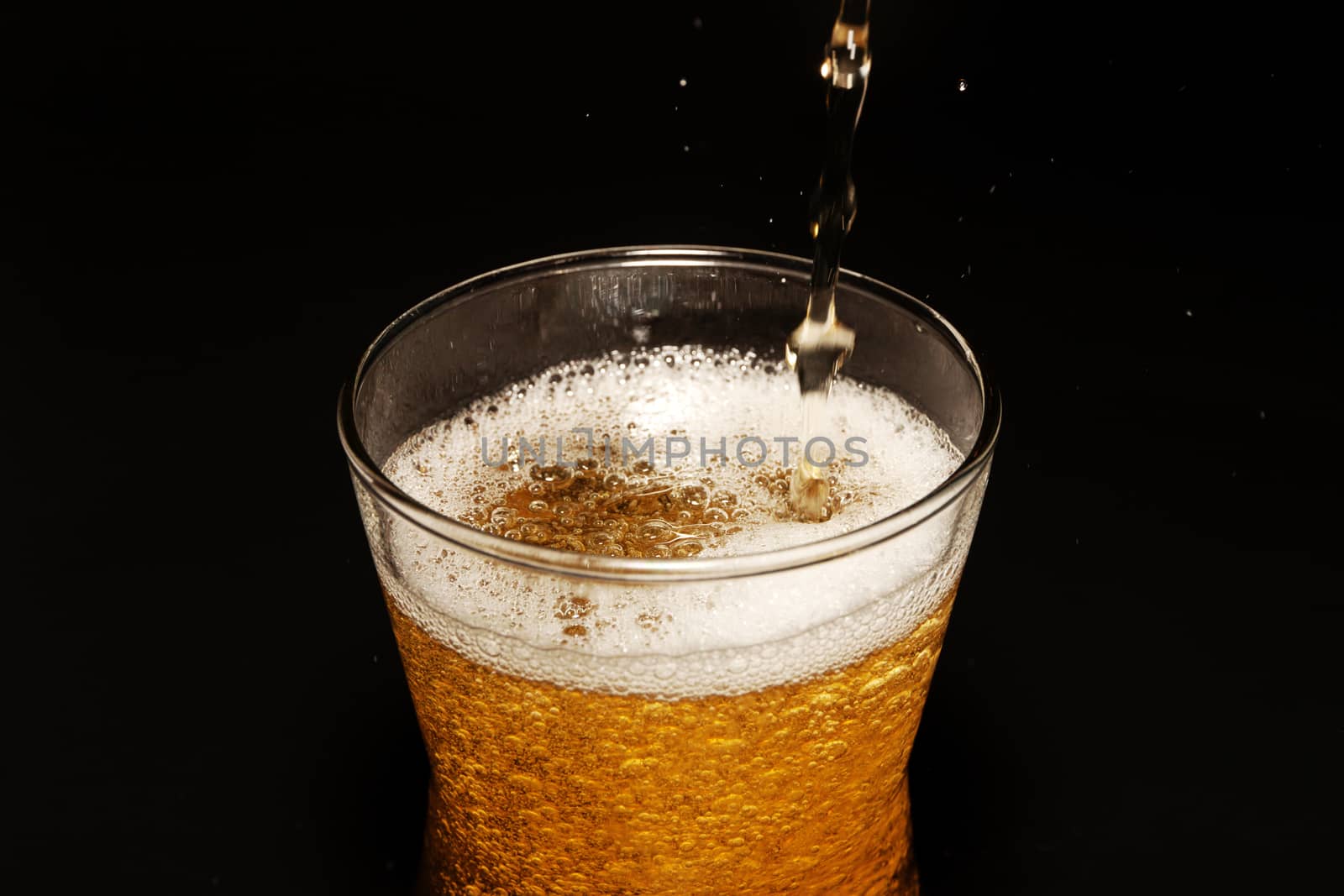 Beer in glass isolated on black background. Pour beer