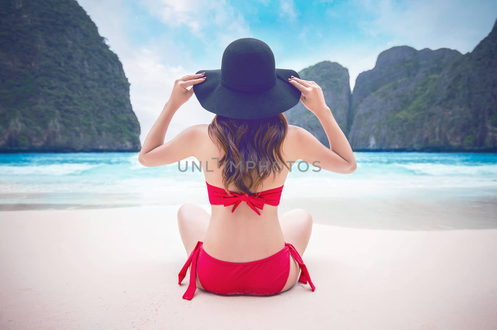 Young woman in red bikini sitting on the beach. Vintage tone.