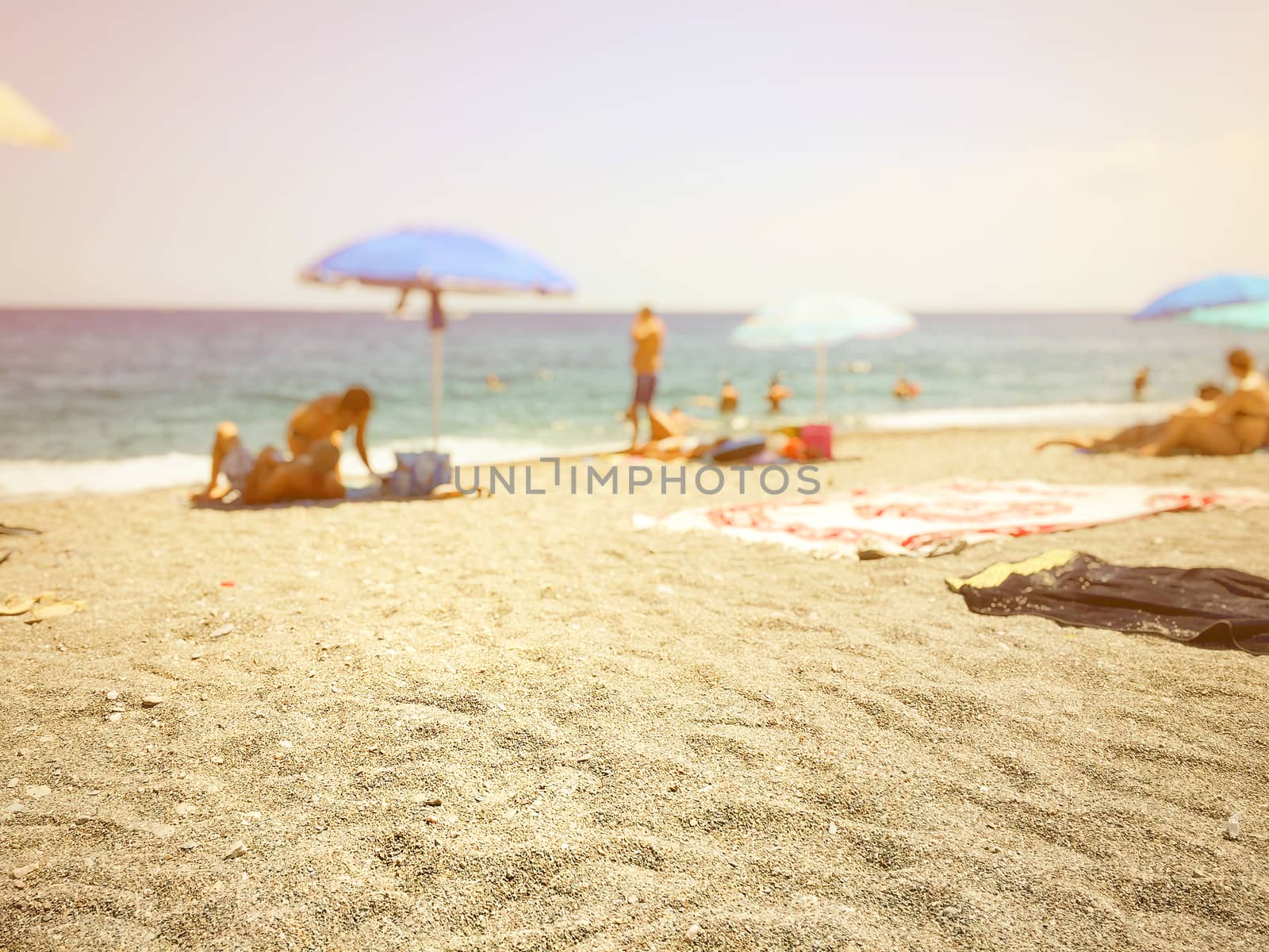 beach sand with blurry people relaxing by the sea in the background 