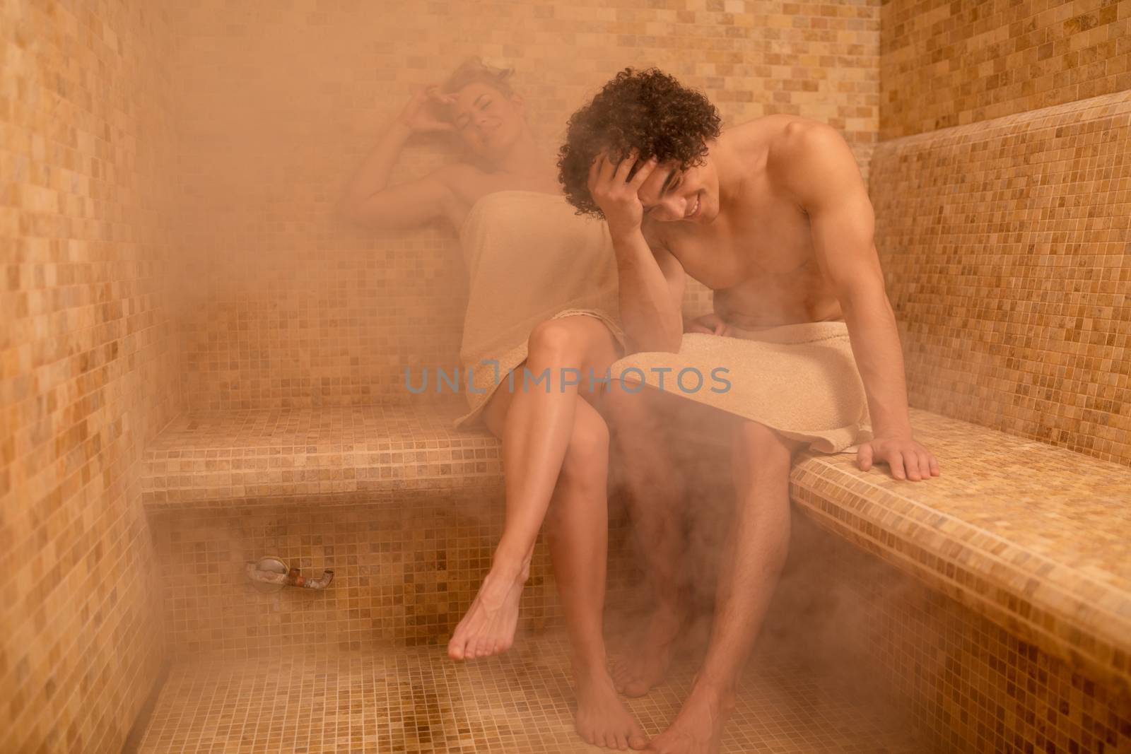 Beautiful young couple relaxing in the steam bathroom at the spa centre.