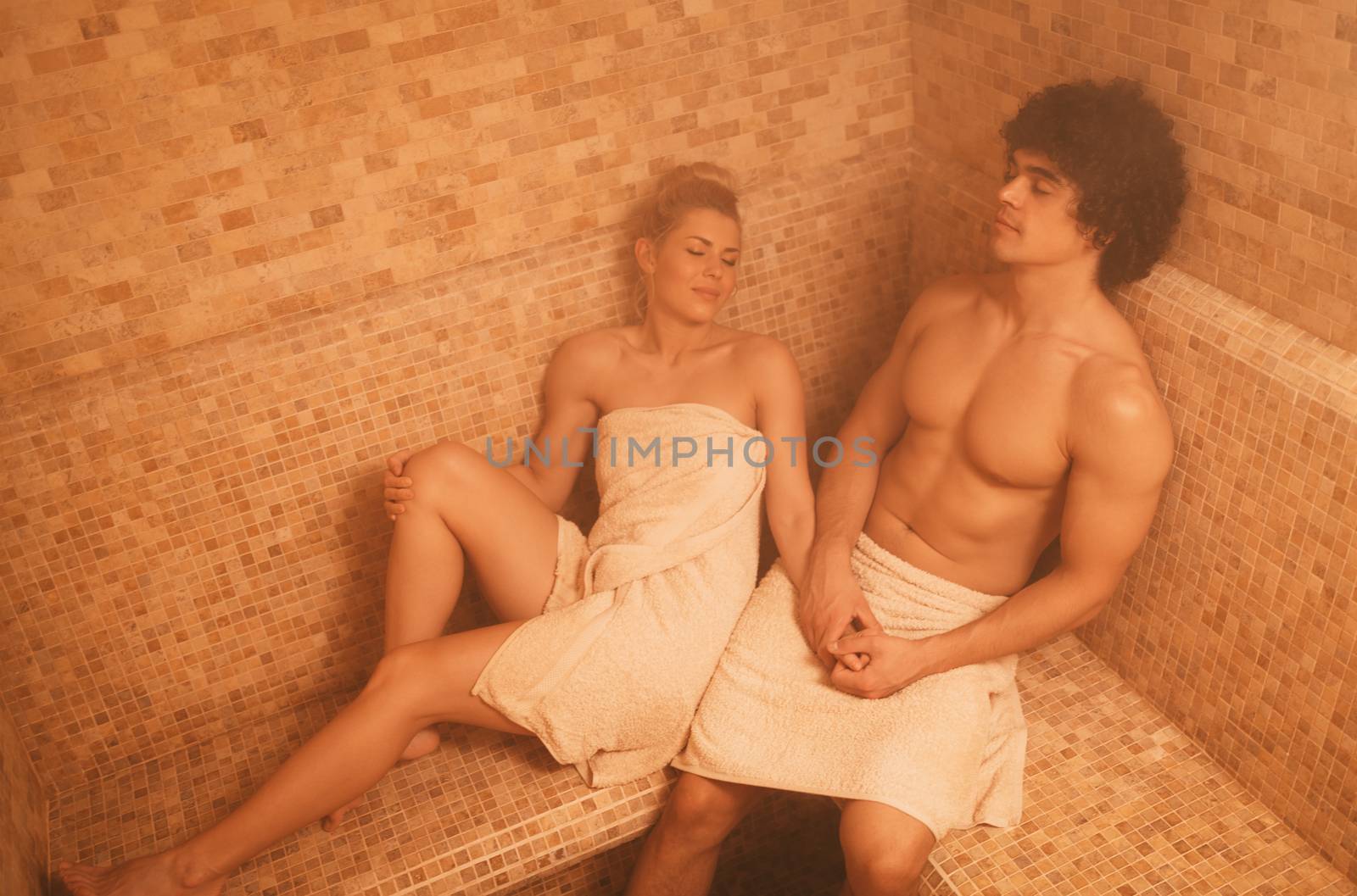 Beautiful young couple relaxing in the steam bathroom at the spa centre.