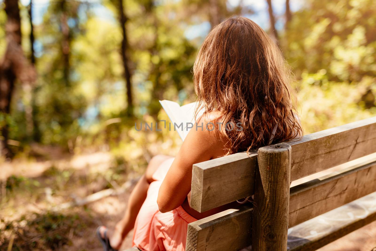 Young woman reading a book while relaxing in the forest.